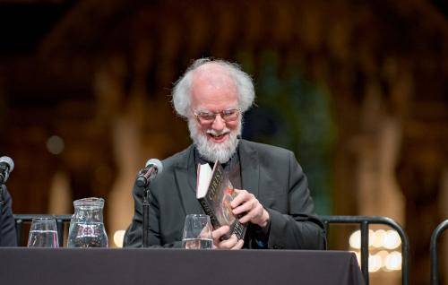 Rowan Williams smiling as he leafs through his book at an event at St Paul's Cathedral