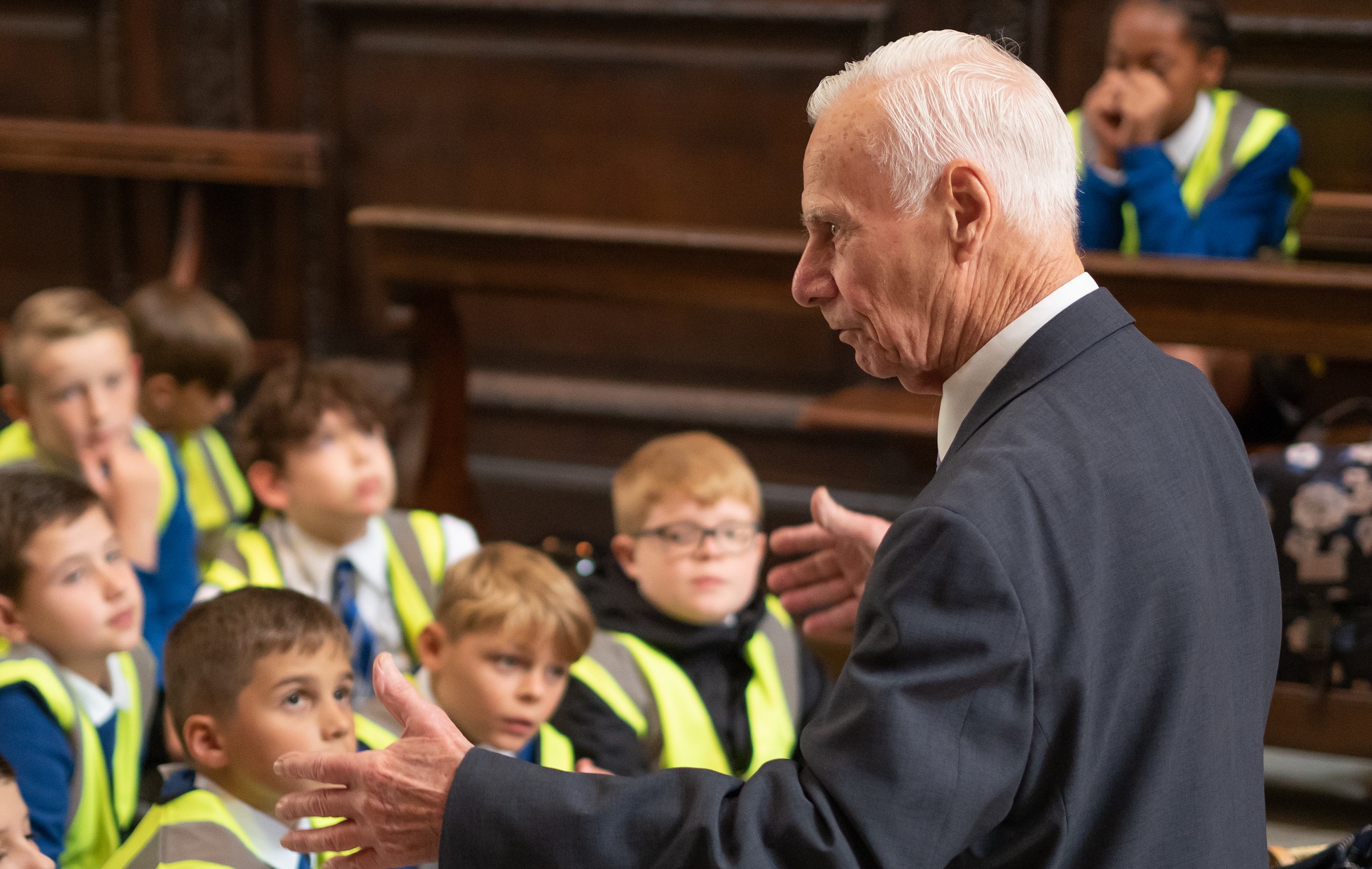 An elderly man talking to a group of primary school children in the cathedral