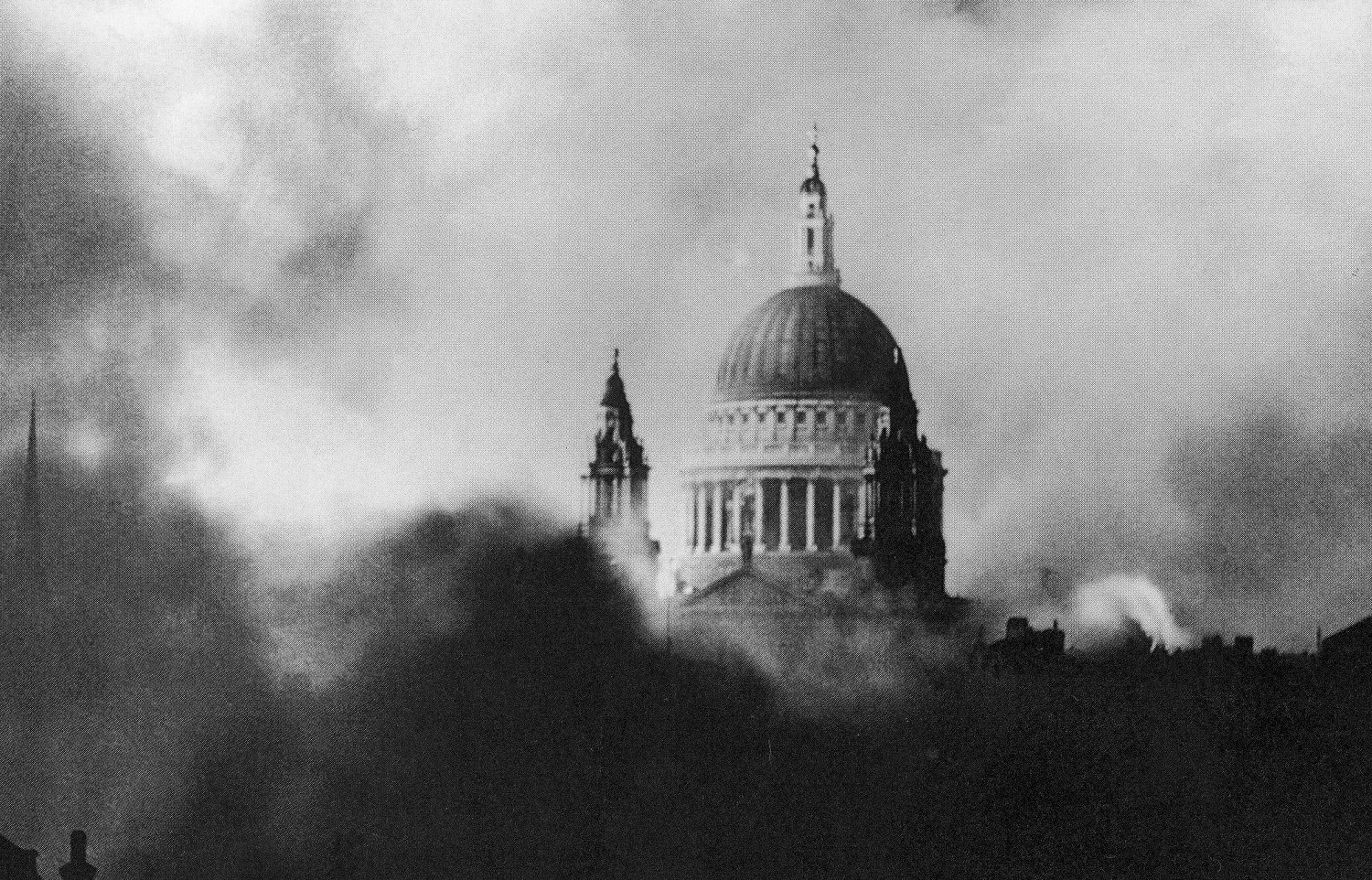 A photograph of St Paul's Cathedral dome surrounded by smoke with bombed out buildings in the foreground
