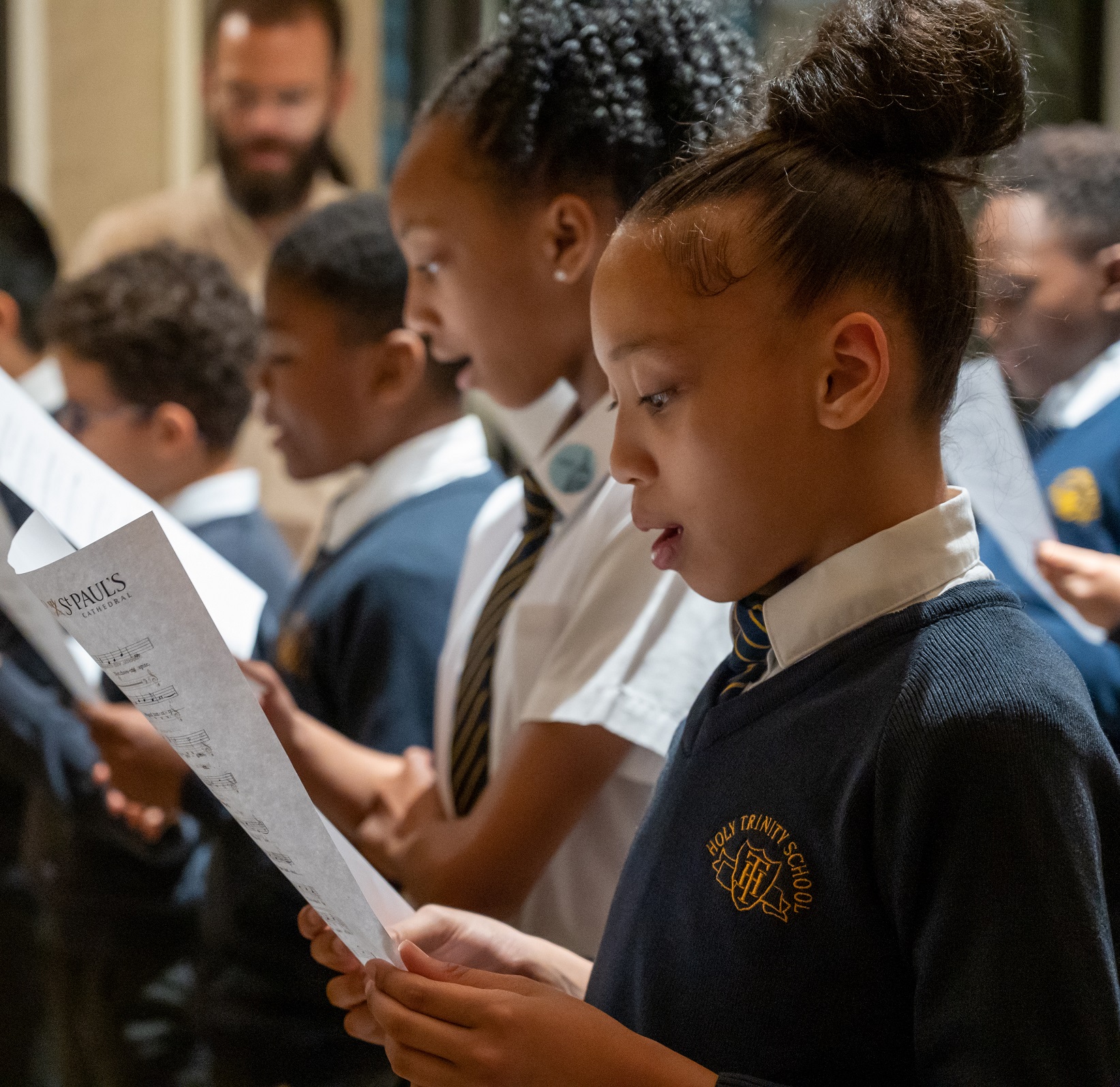 girls and boys in school uniform singing from sheet music