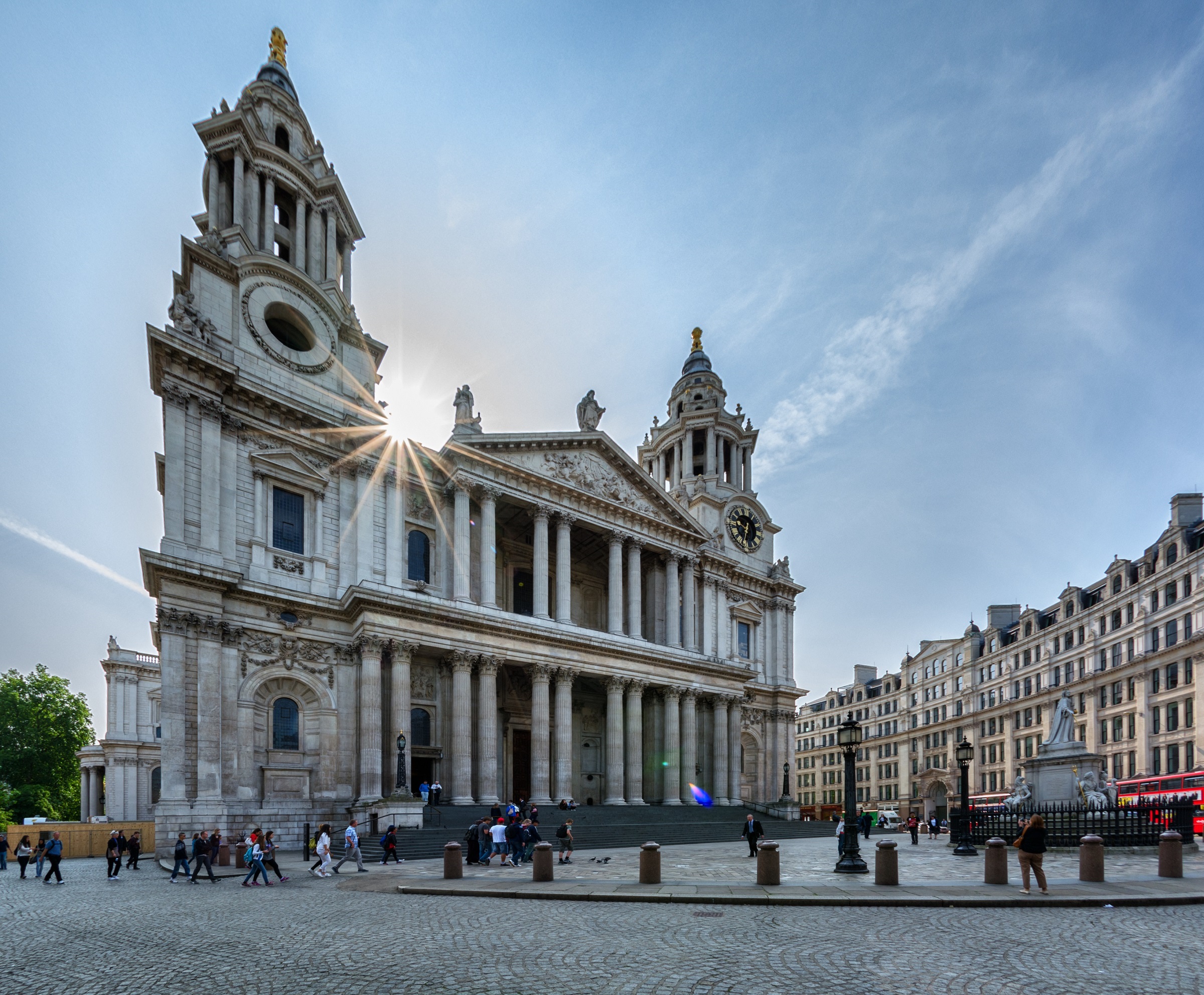 The west front of the cathedral with tourists milling round and sun shining over head