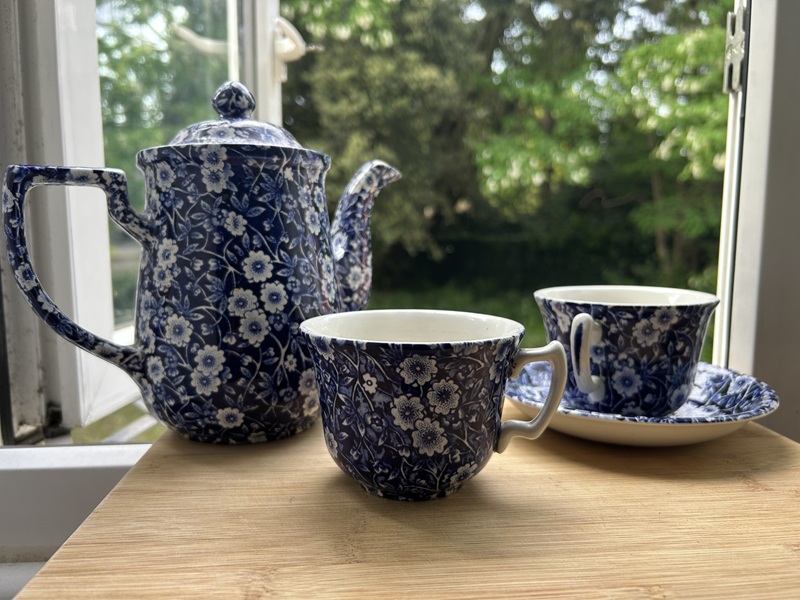 A blue calico teapot with two cups and a saucer