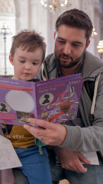 father and son looking at activity book together