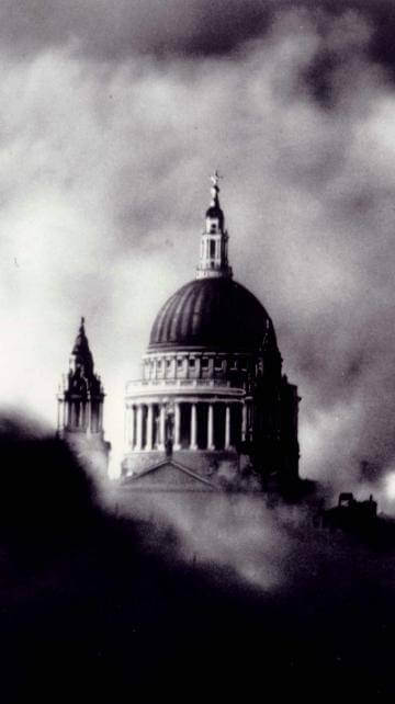 a black and white image of St Paul's Cathedral dome visible above a cloud of smoke at night
