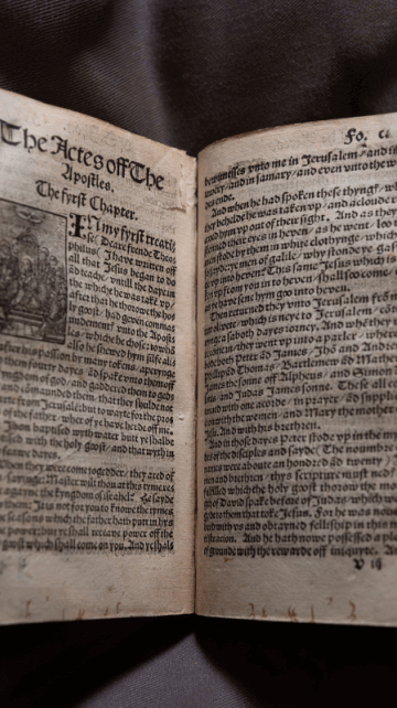 The 500 year old Tyndale bible open on a grey background