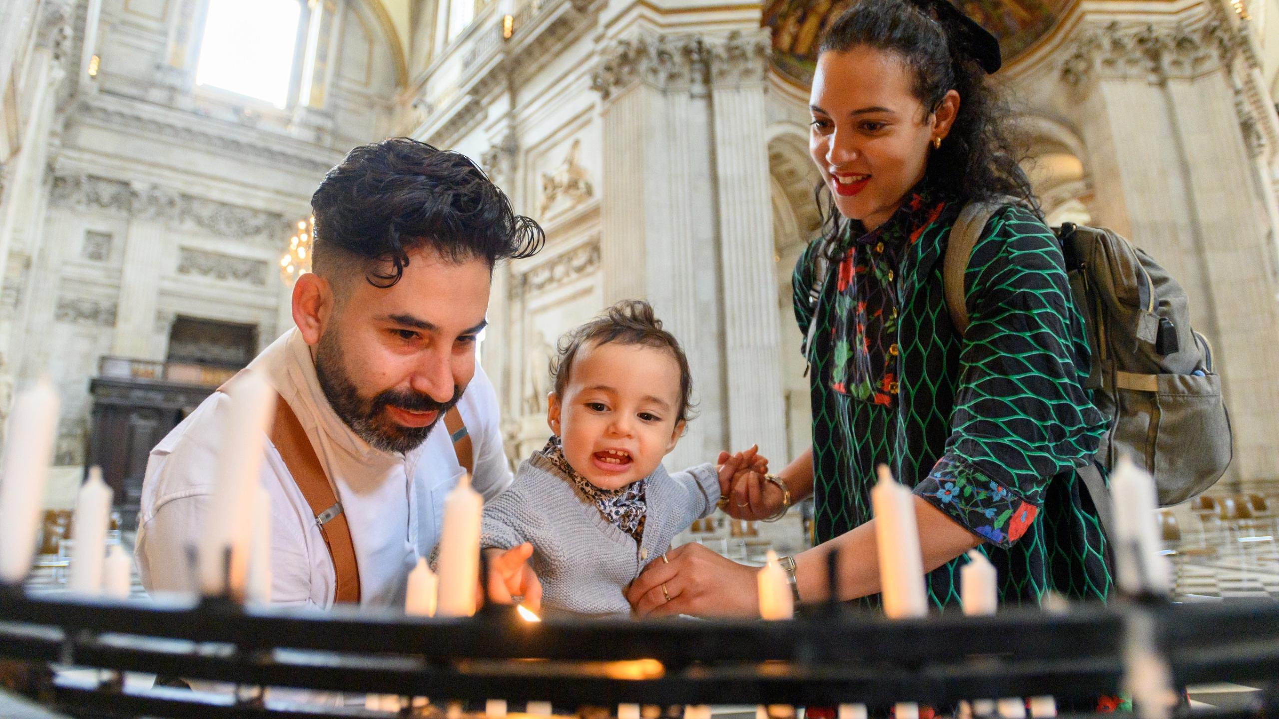 young family with baby lighting candles prayer