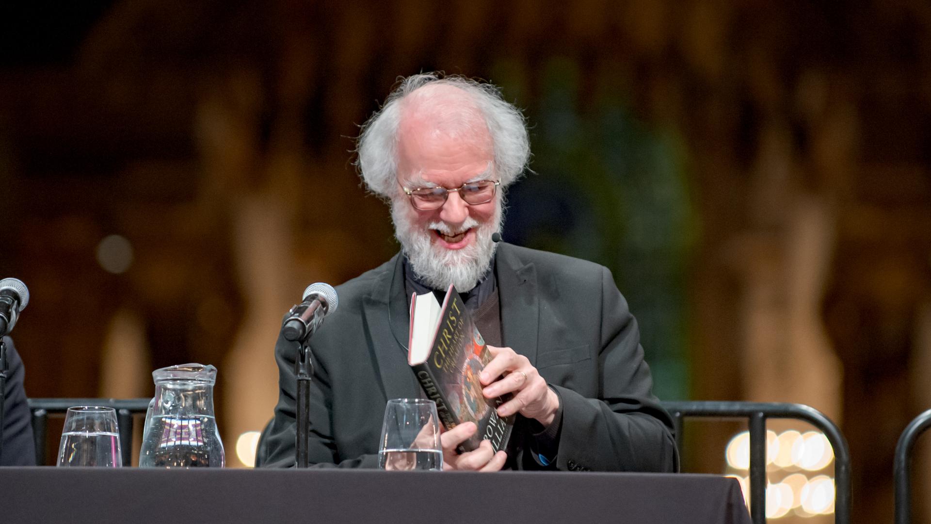 Rowan Williams smiling as he leafs through his book at an event at St Paul's Cathedral