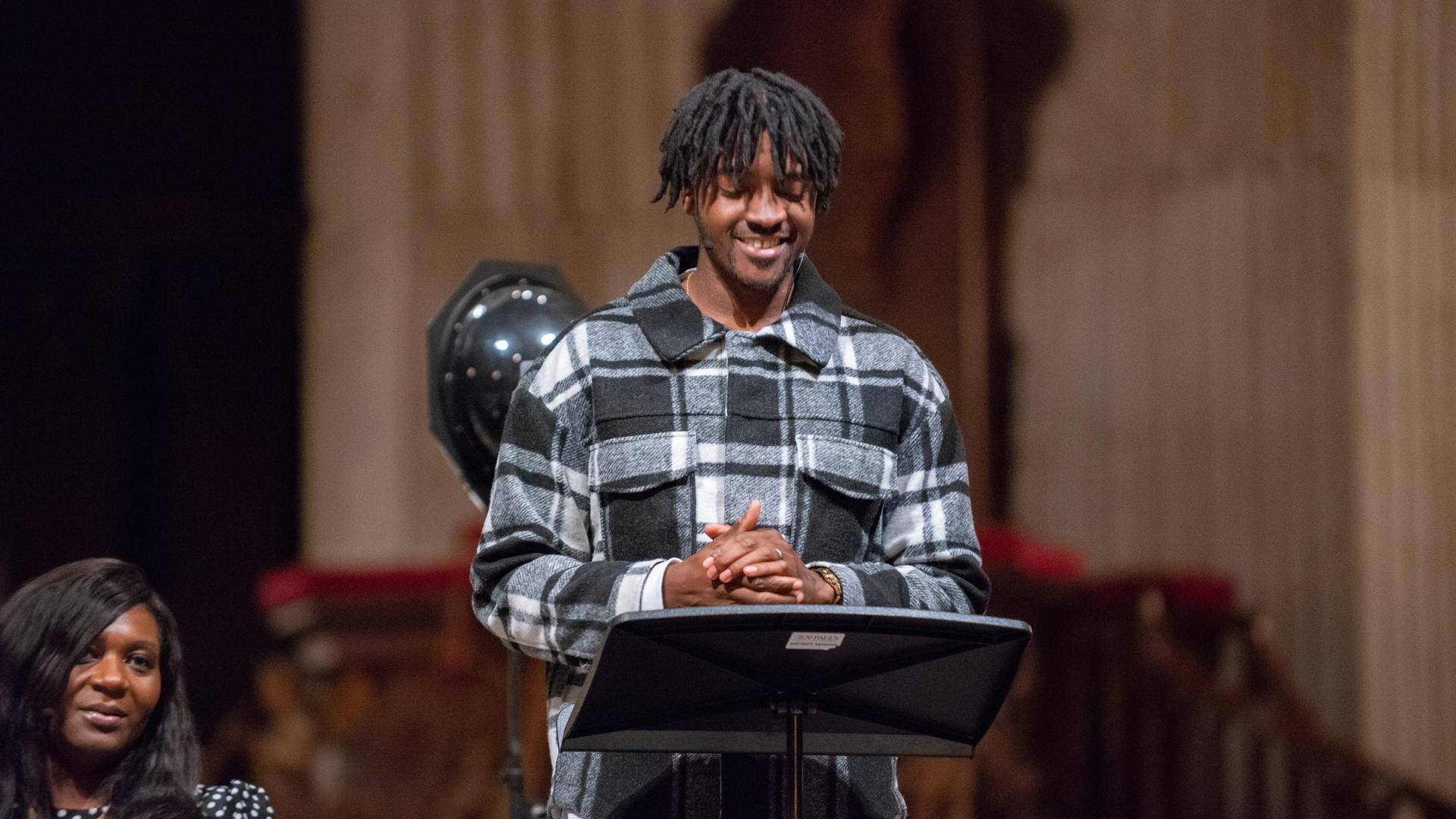young black man speaking at pulpit as part of special service