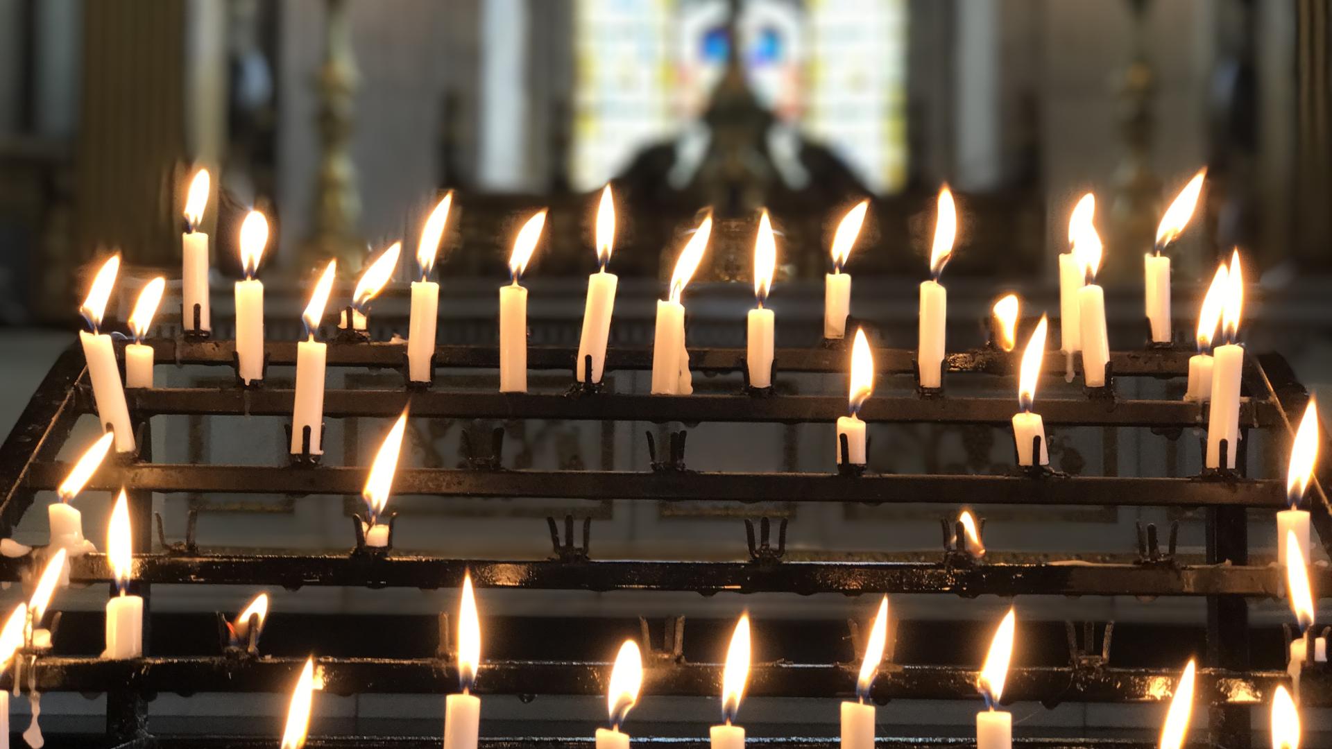 A series of lit candles on the candle stand in the cathedral
