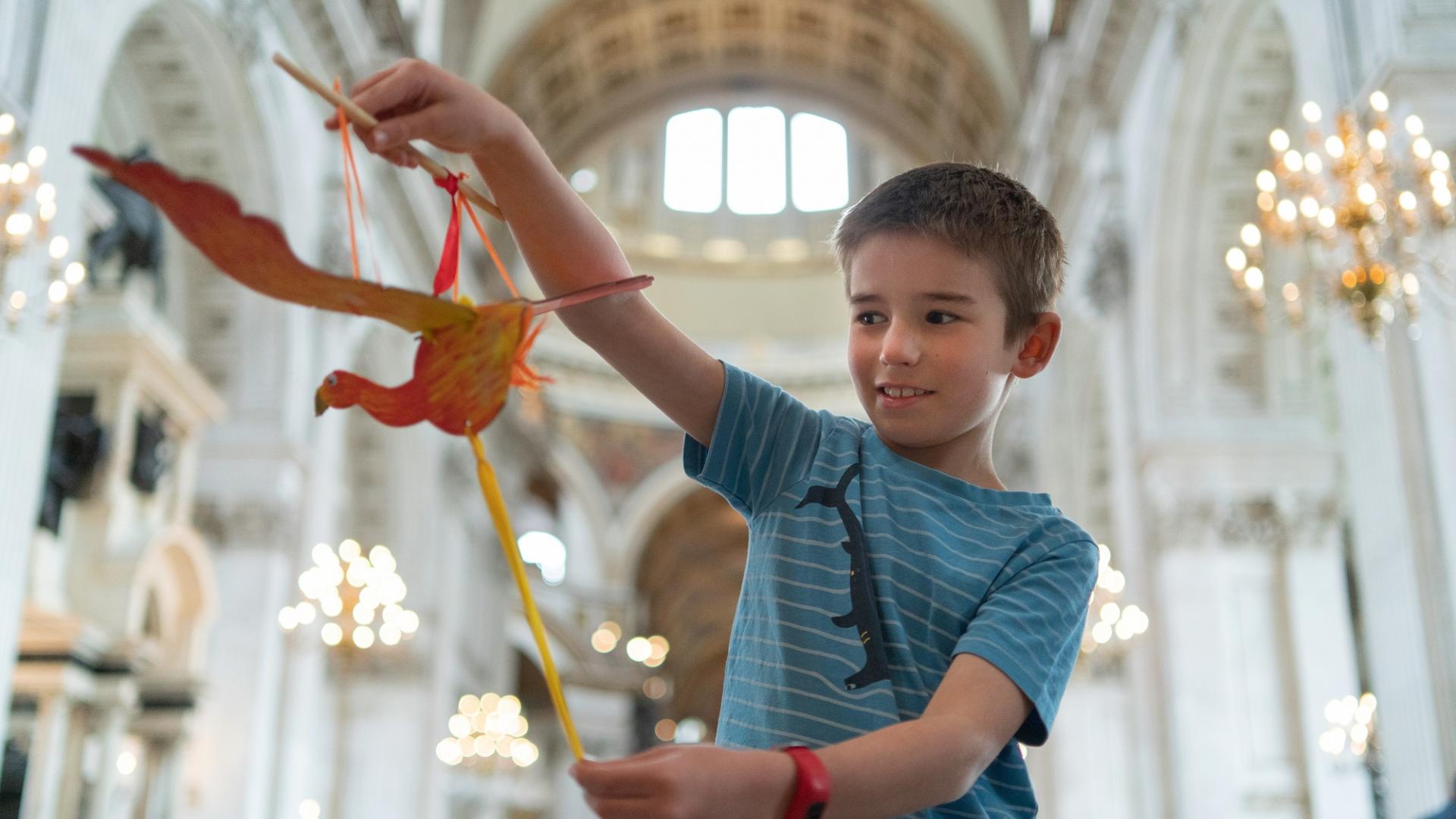 A young boy holds a paper model of a phoenix inside the Cathedral