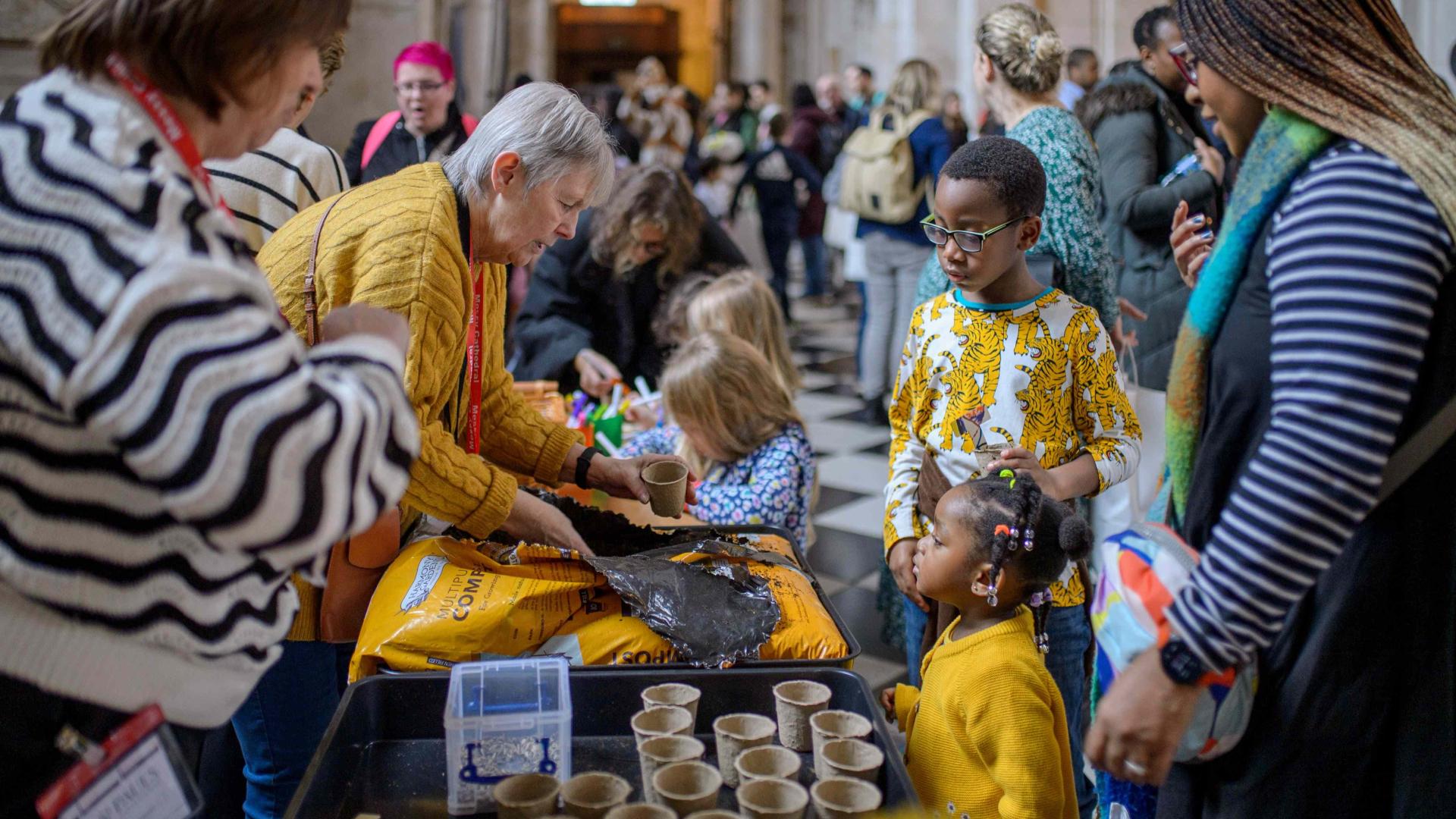 A group of young children and their families gathered around a table filled with craft activities.