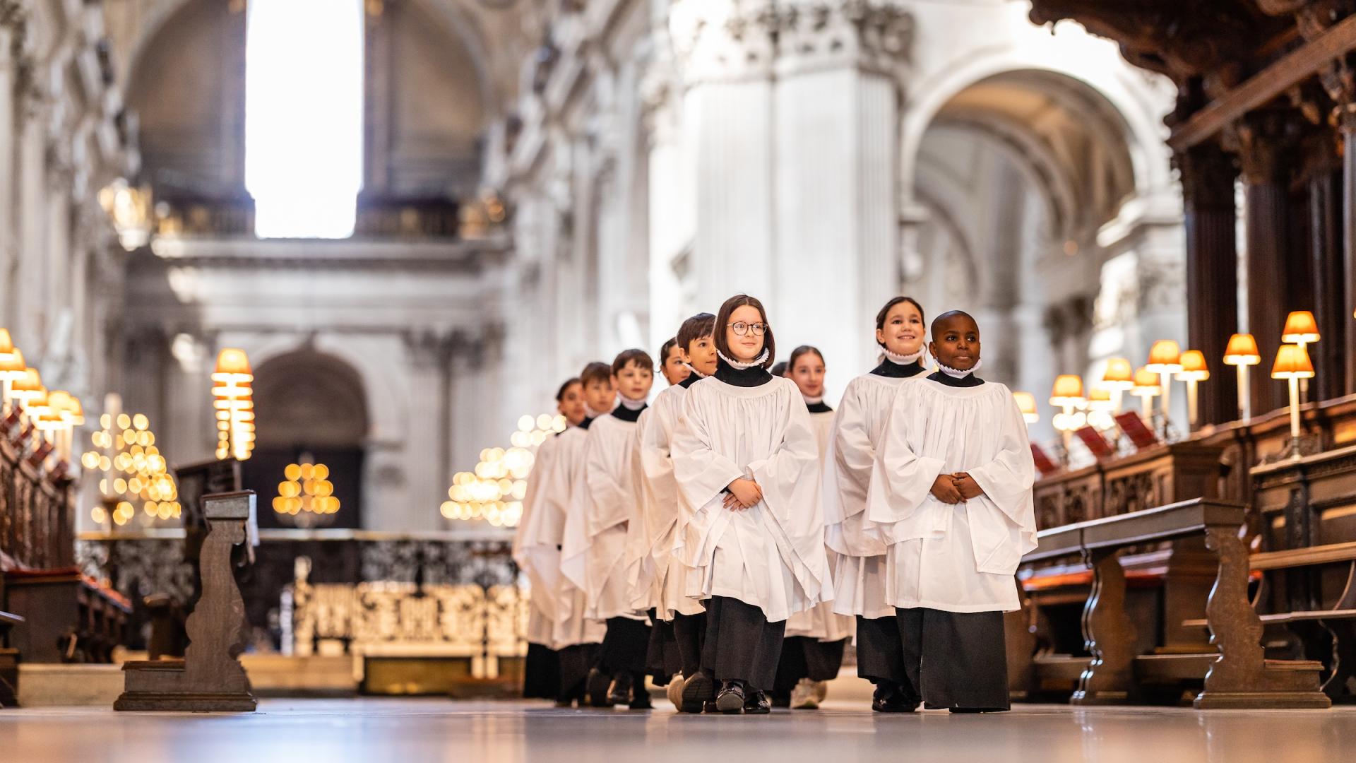 Girl and boy choristers in robes walking in the quire