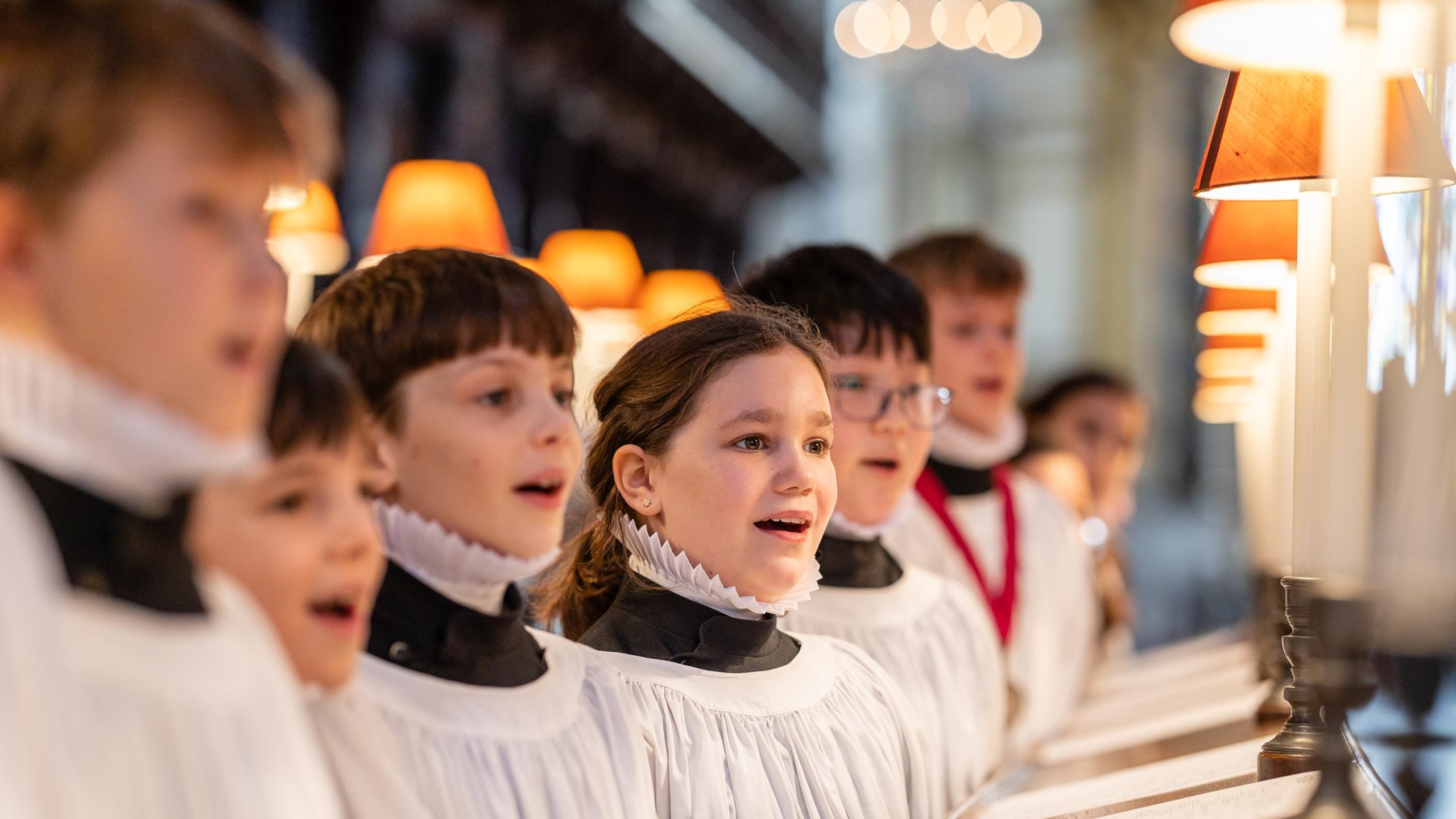 Girl and boy choristers in robes singing in the quire
