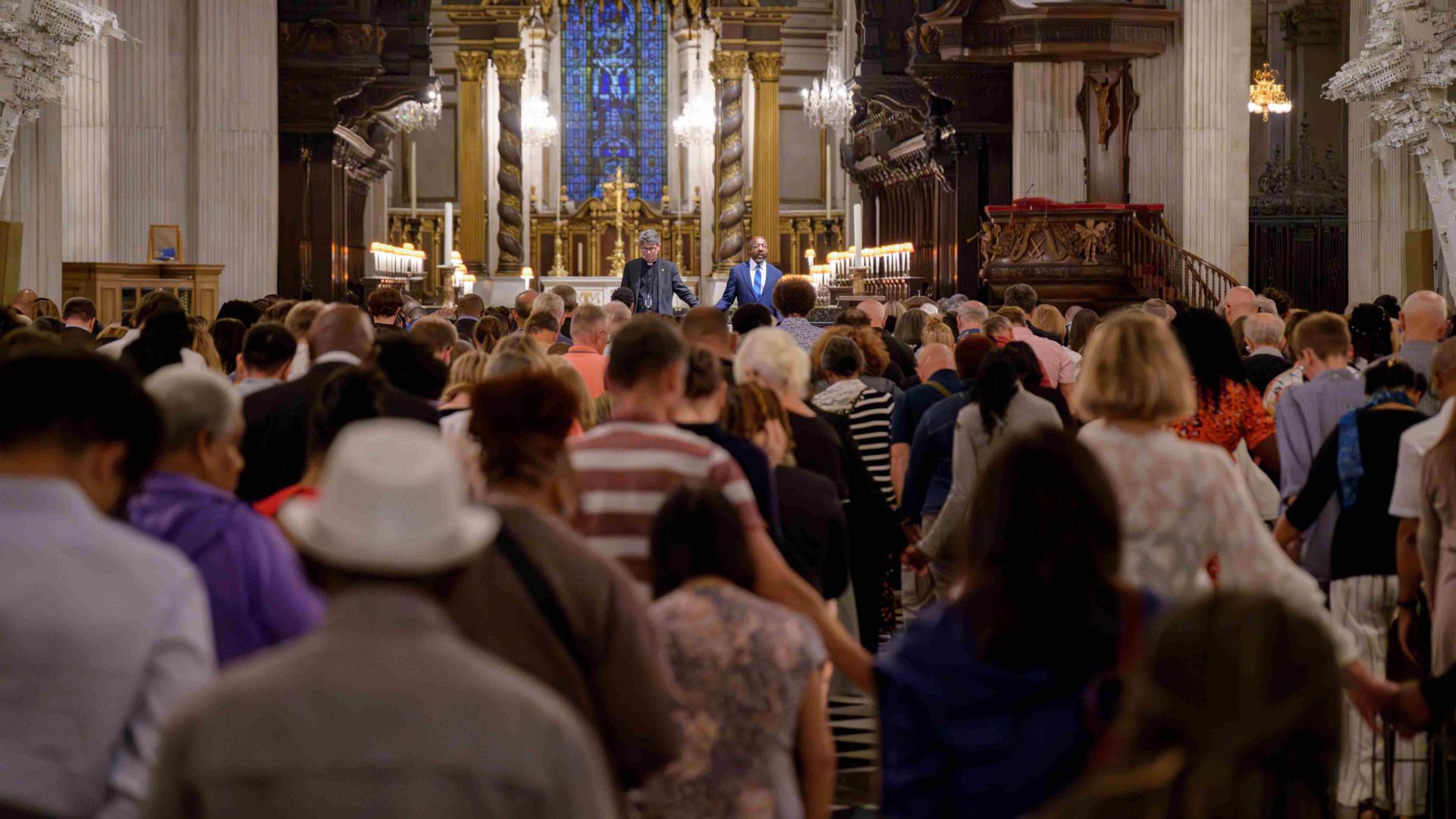 Revd Raphael Warnock and Dean Andrew Tremlett pray with a congregation during a learning event