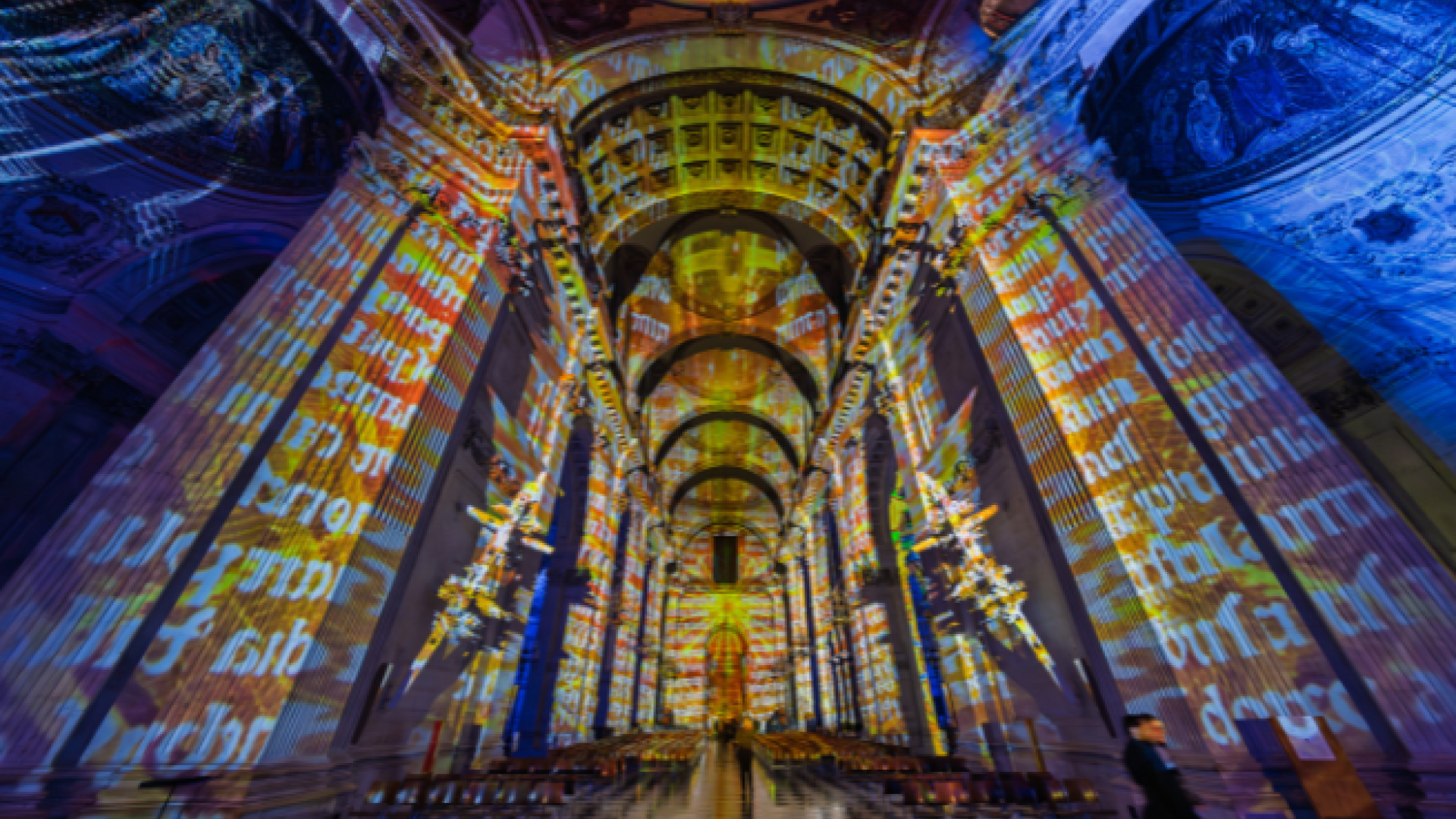 The nave of St Paul's with a projection of a manuscript over orange and blue lights.