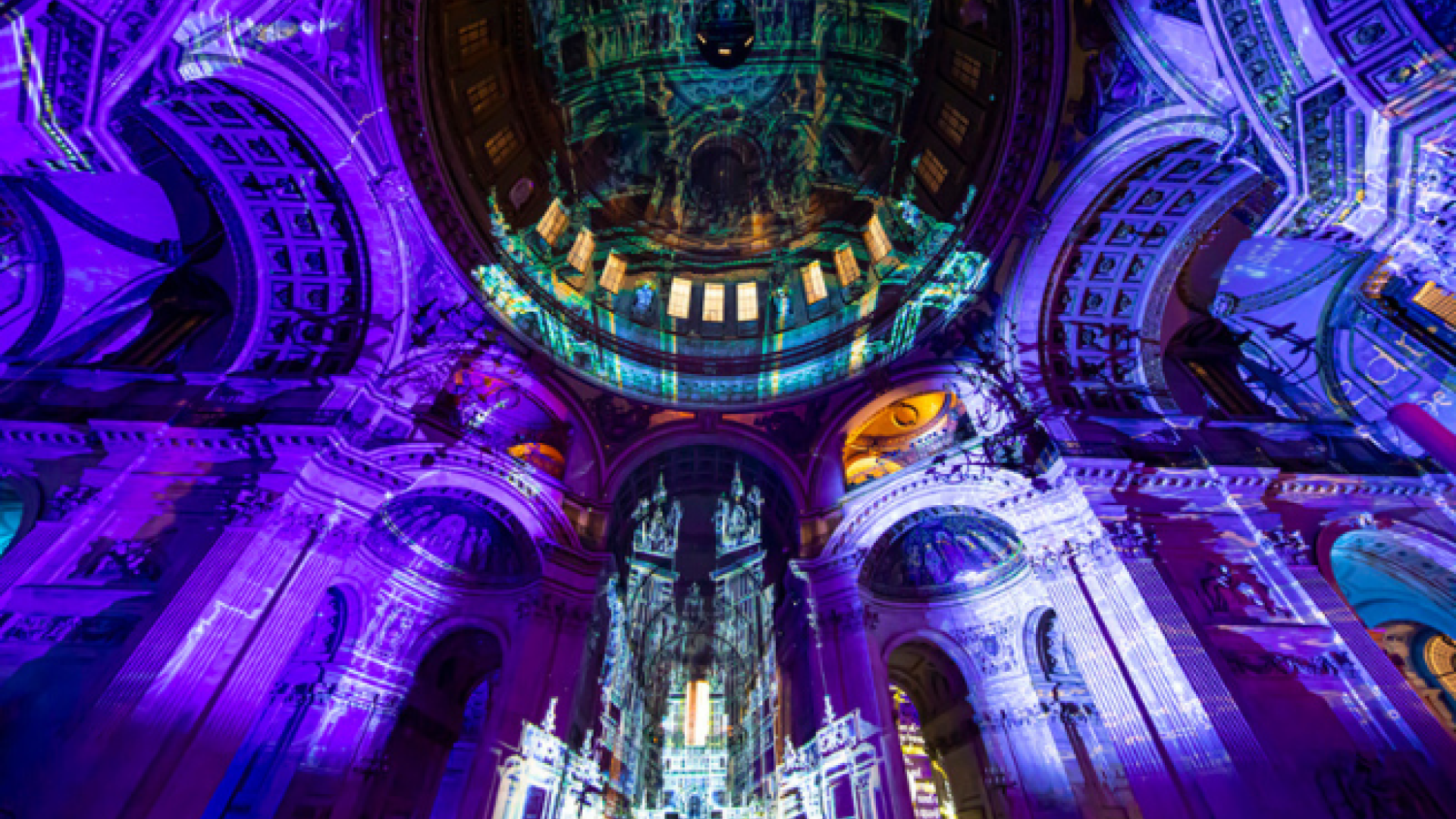 The dome and south transept lit with purple projections, featuring an image of the Old St Paul's Cathedral.