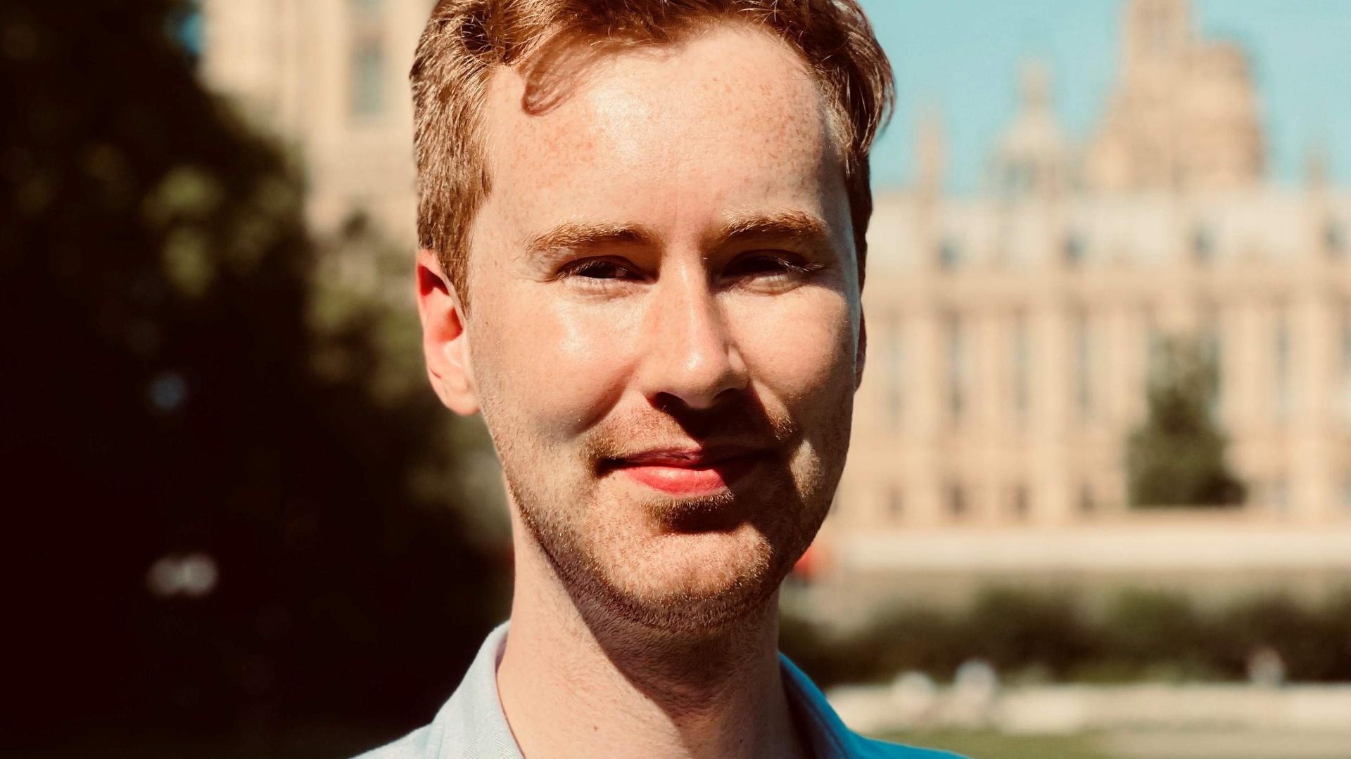 James Roberts, a white male wearing a blue shirt with collar standing in front of a cathedral