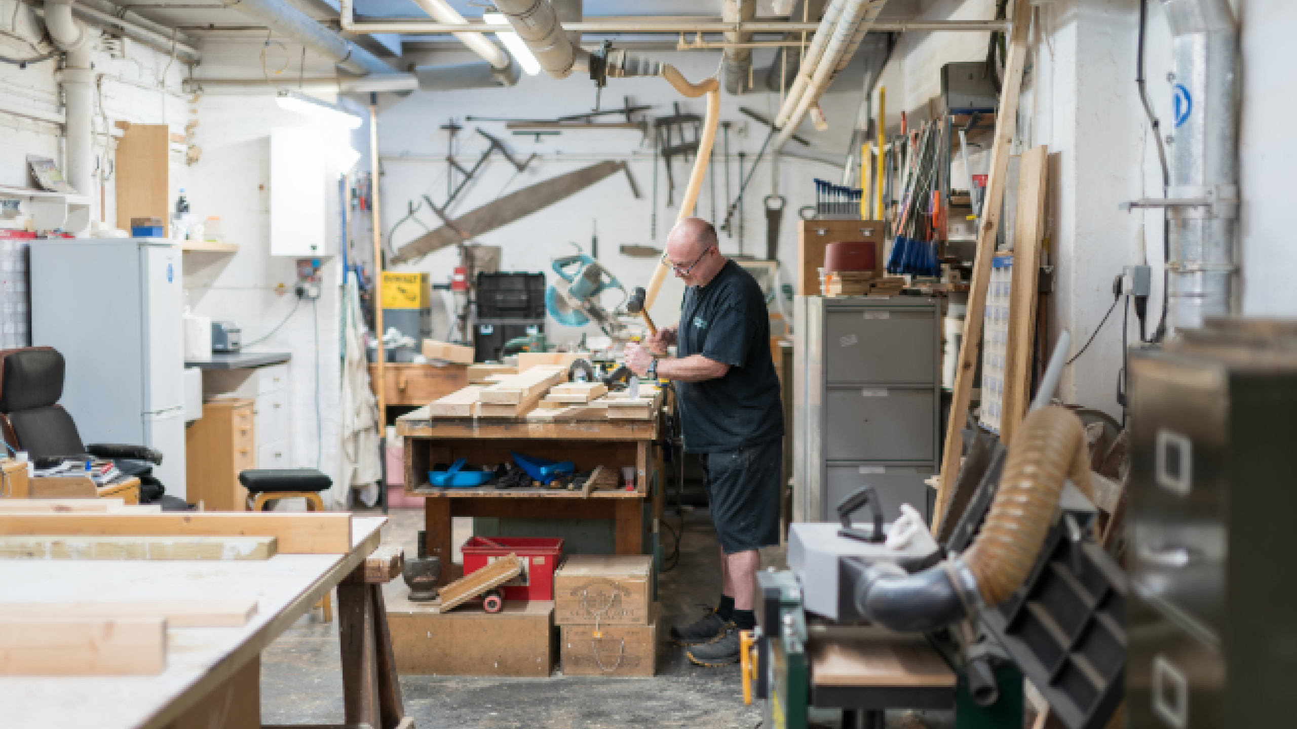 Carpenter using tools to mend a piece of furniture in a workshop
