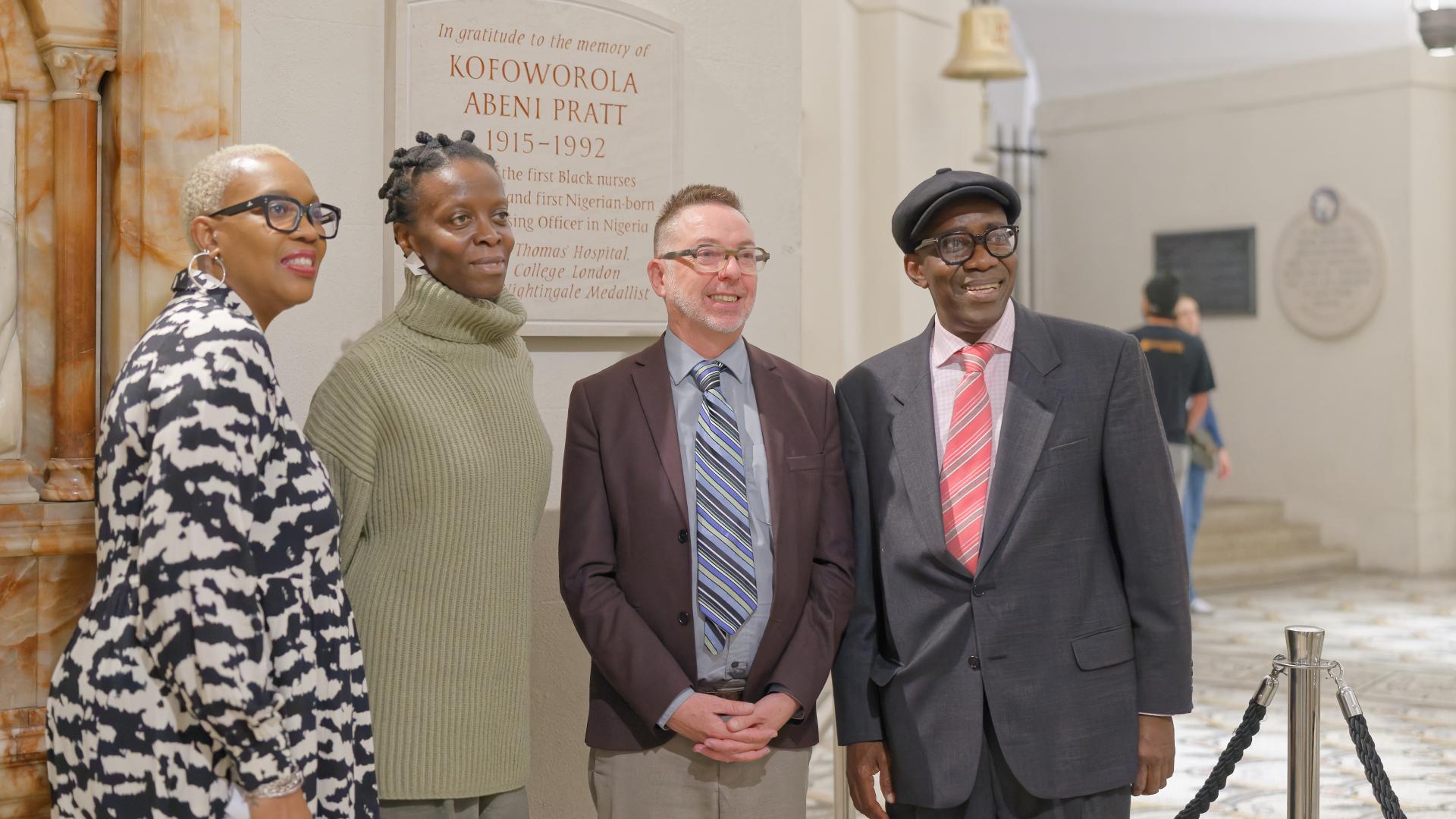 A group of people stand in front of a memorial plaque in the Crypt.