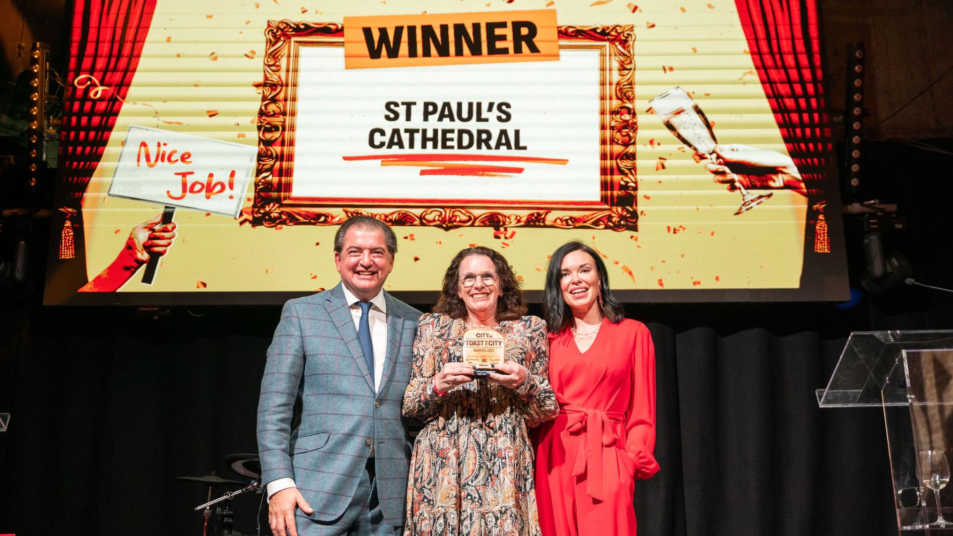 Kim Newland holds award with presenters in front of a screen that says 'Winner: St Paul's Cathedral: Best Cultural Experience'