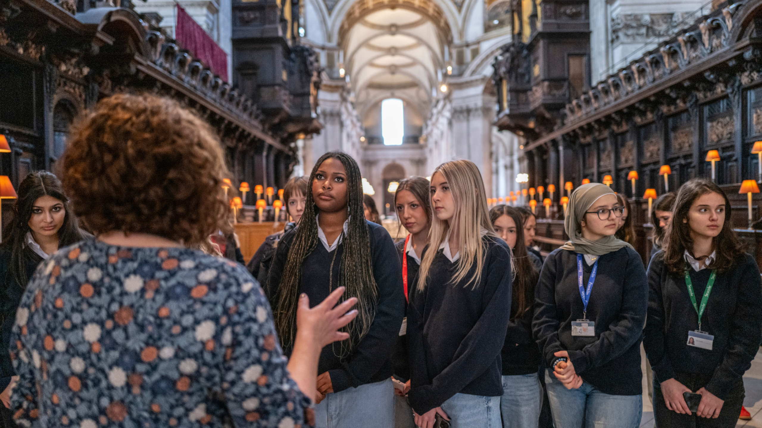A school group stands in the Quire listening to Charlie from the Learning team giving a talk.