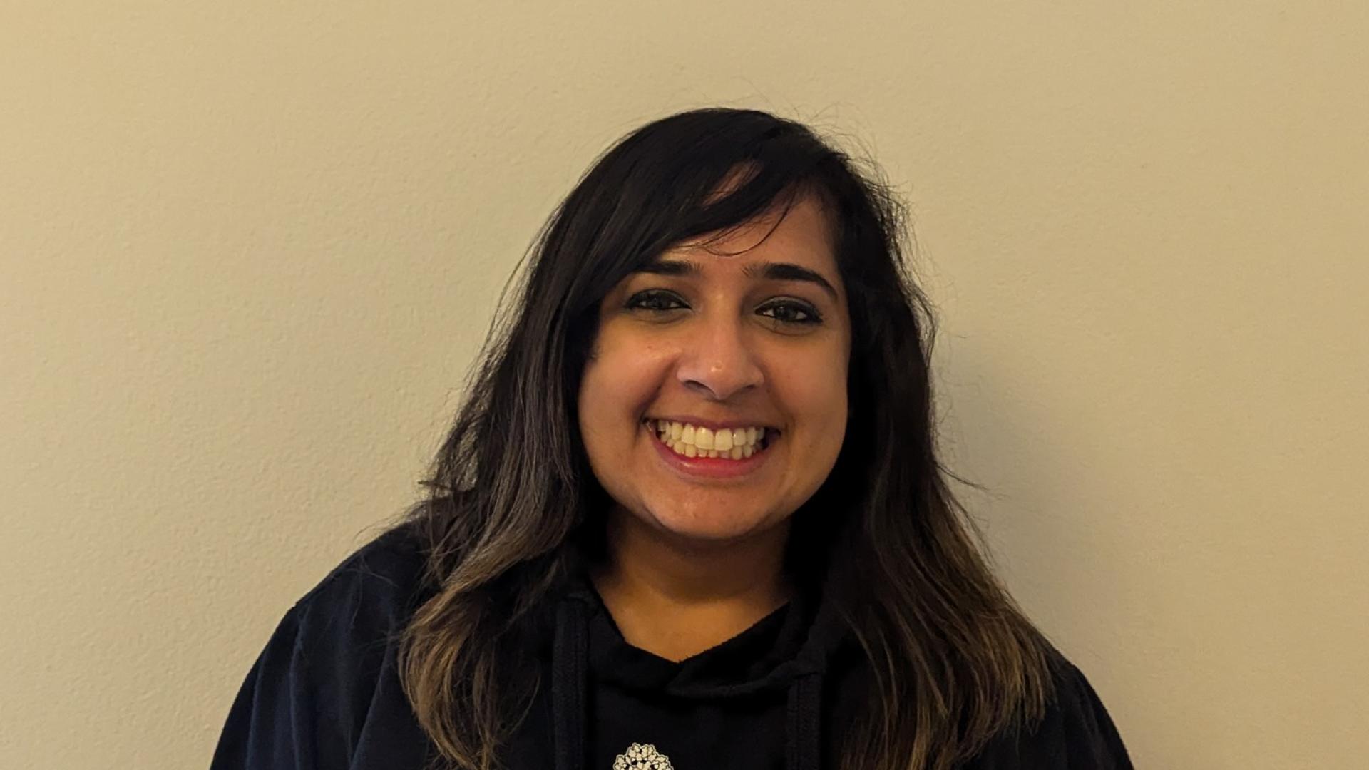 A woman with long dark hair wearing a black hoodie.