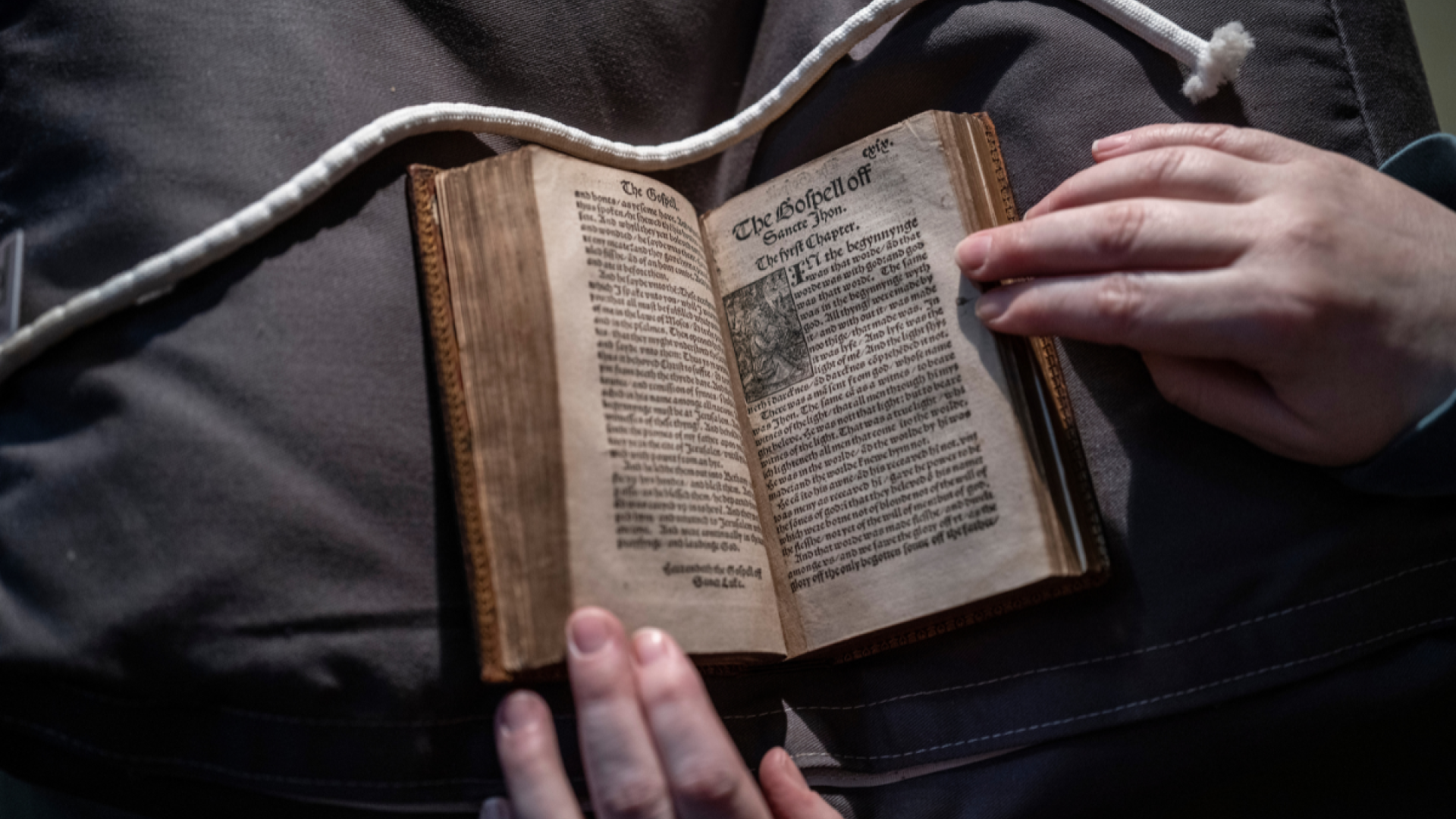 A person holding the 300 year old Tyndale bible on a grey background