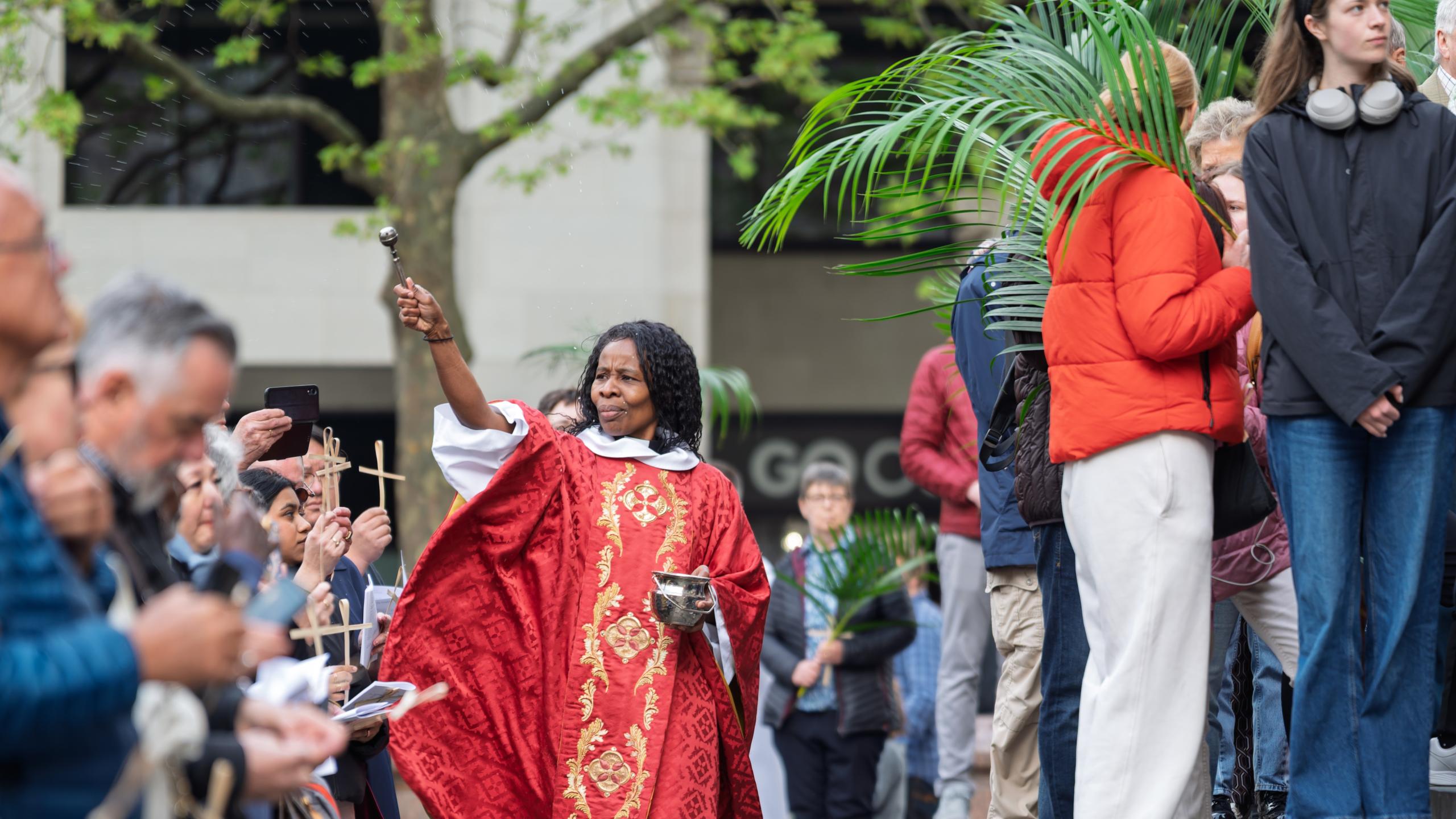 Canon Steward Catherine Okoronkwo blesses the crowd on the West Steps on Palm Sunday.
