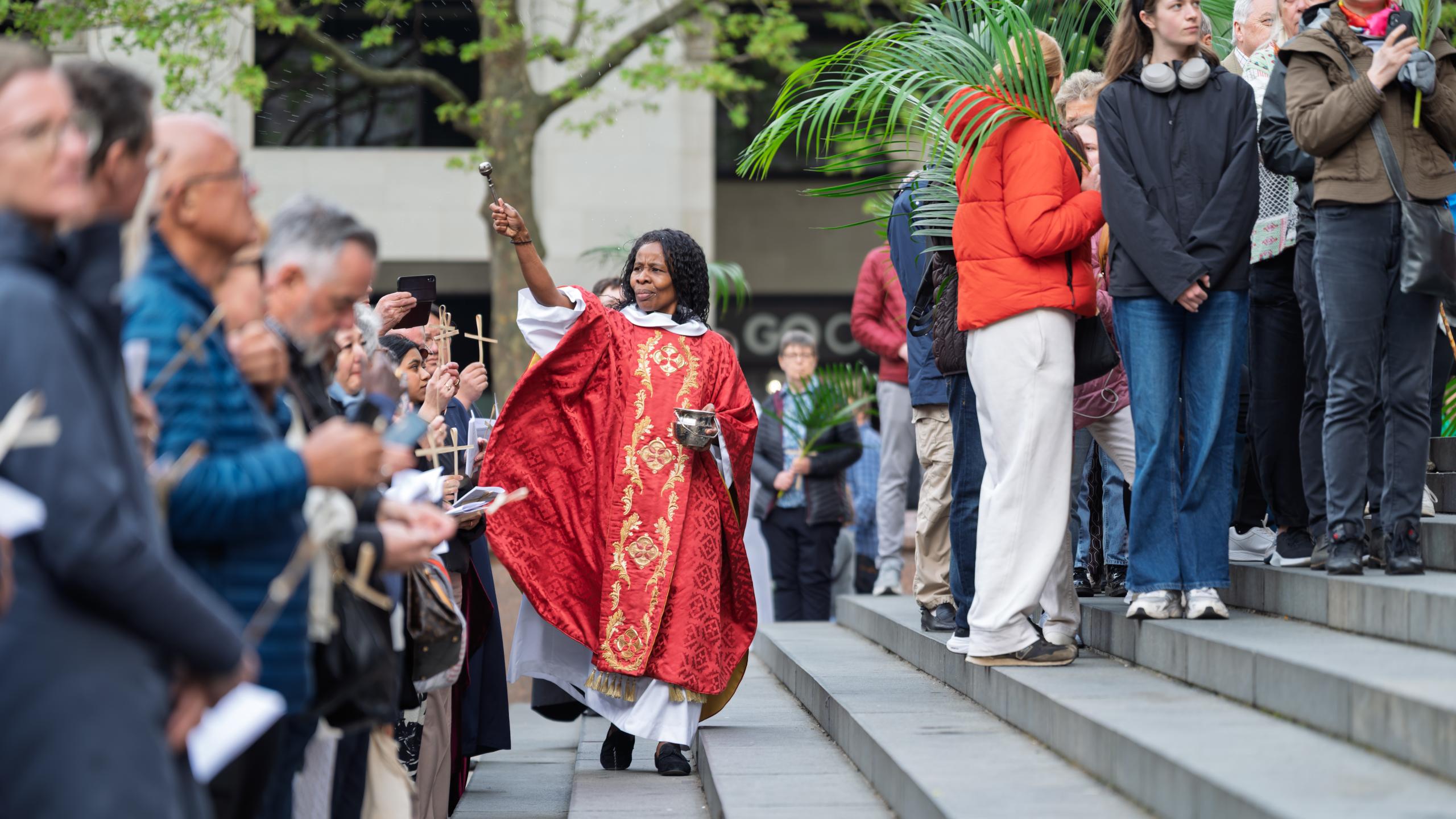 Canon Steward Catherine Okoronkwo blesses the crowd on the West Steps on Palm Sunday.