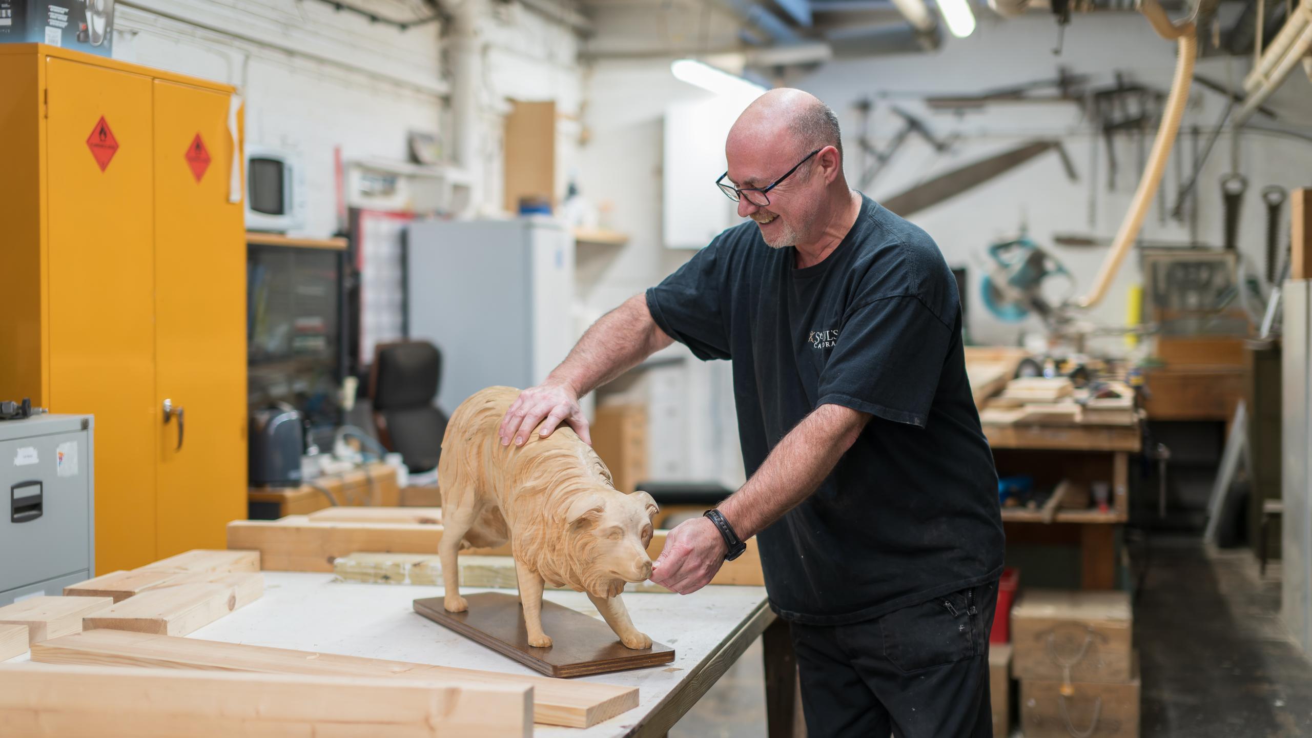 One of our carpenters in the workshop with a wooden dog.