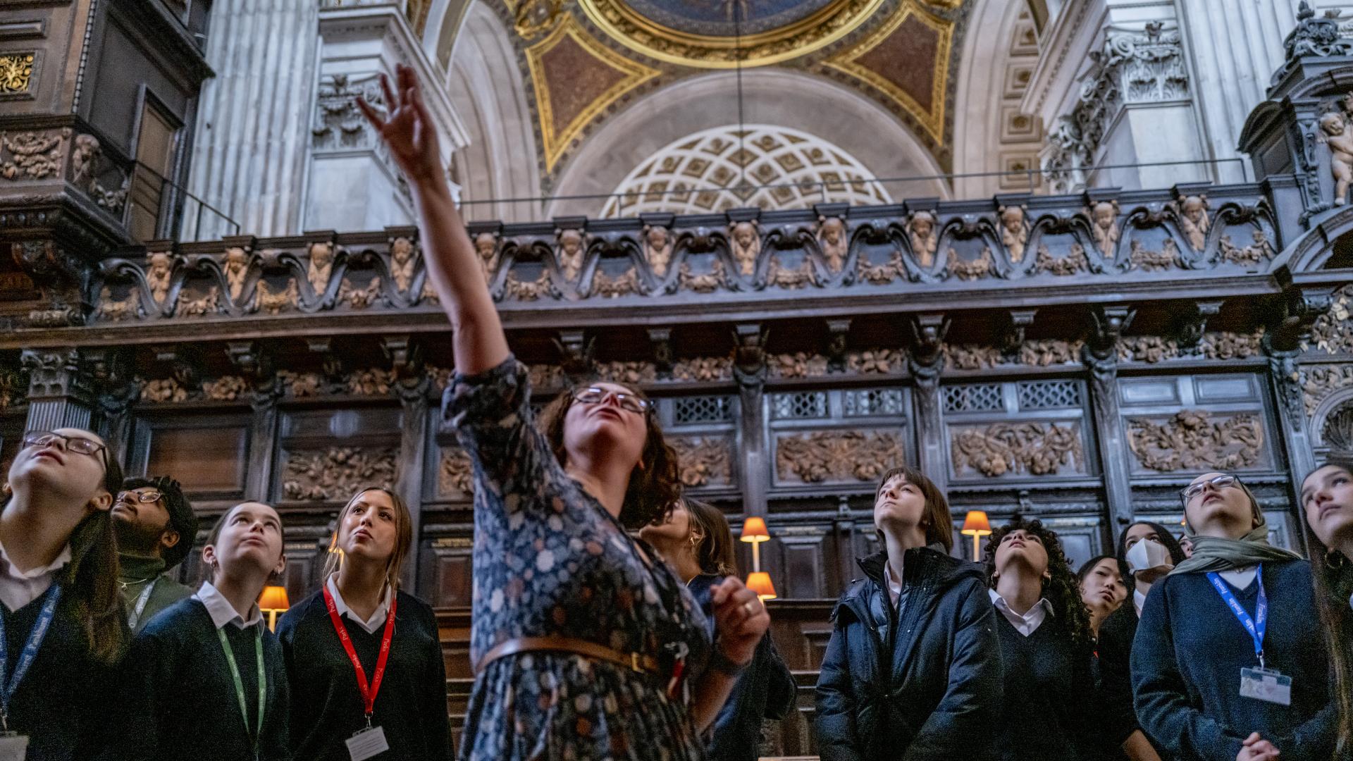 teacher pointing up above heads as children around her look up