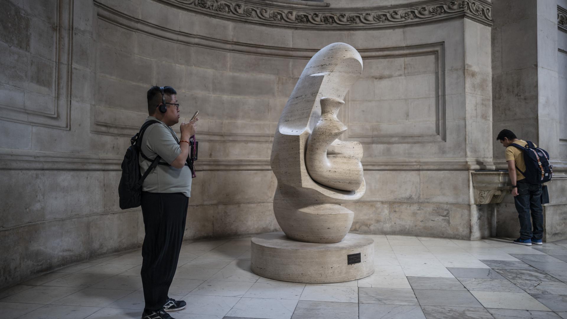 A visitor photographs Mother and Child: Hood by Henry Moore.