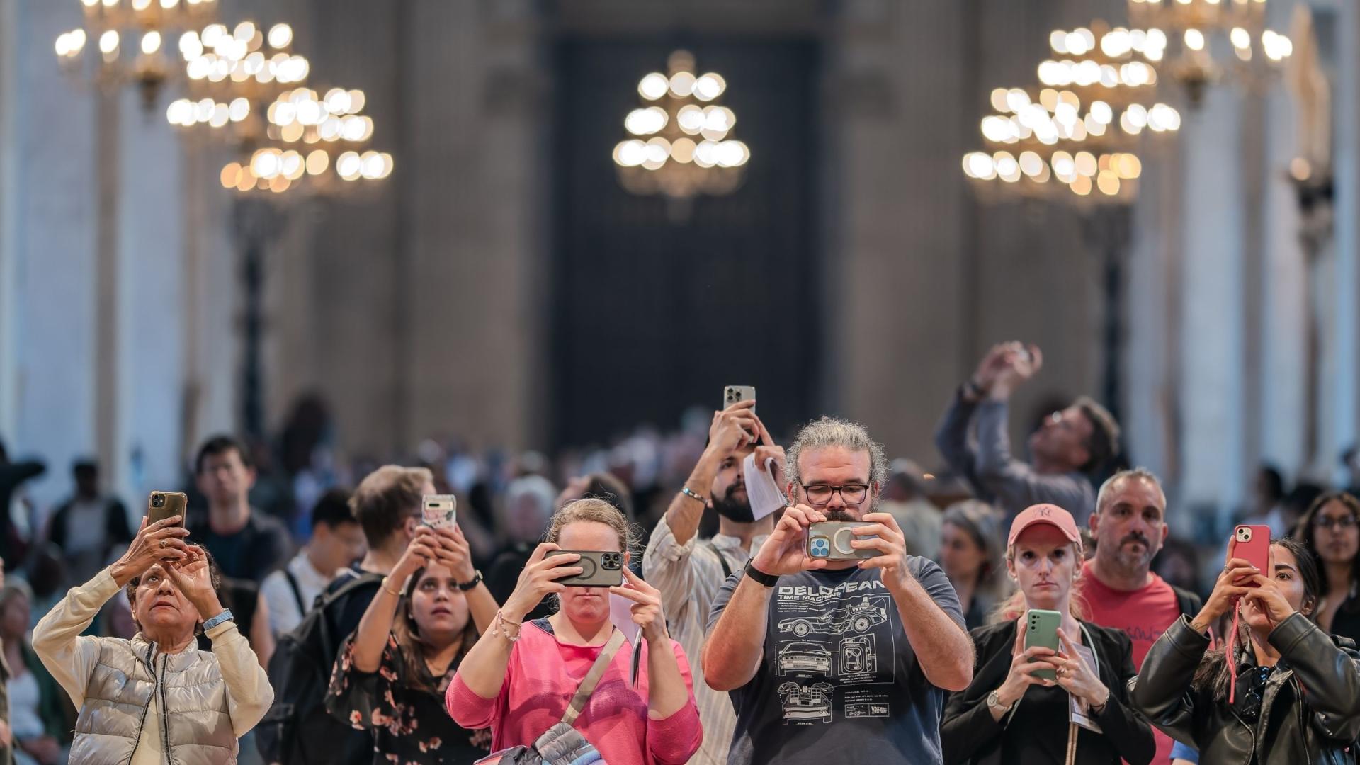 Visitors to St Paul's Cathedral holding up their phones to take photos
