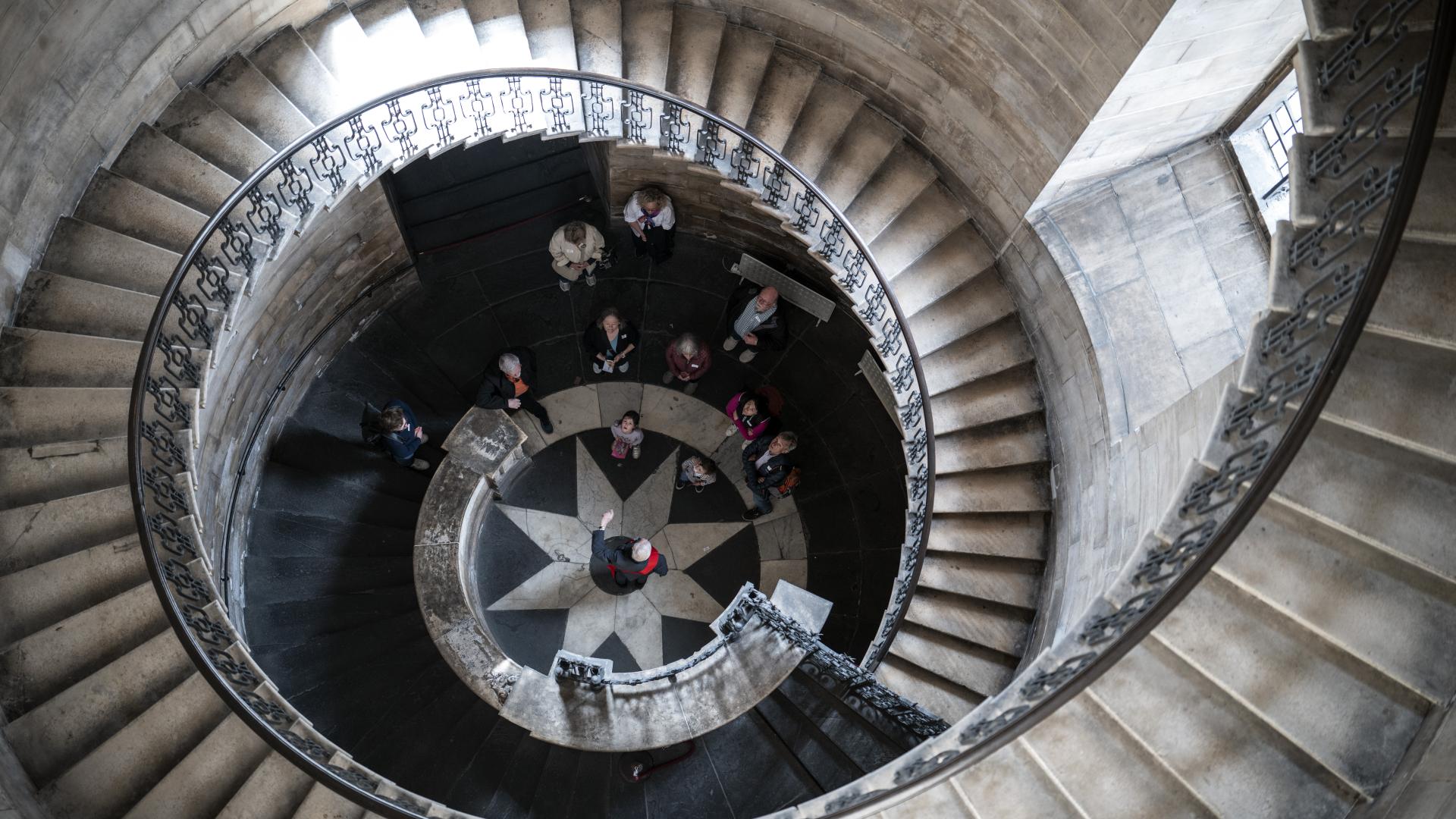 Looking down from the top of the geometric staircase, with visitors at the bottom.