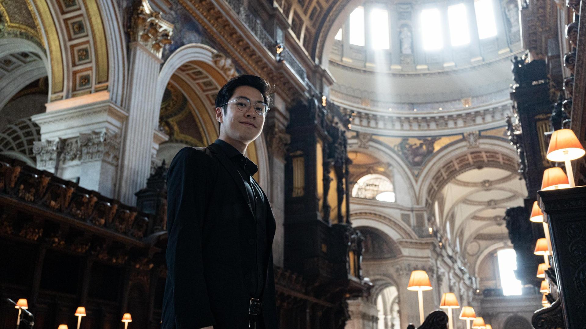 Jeremy Ng, Organ Scholar, stands in the Quire with the organ behind him.