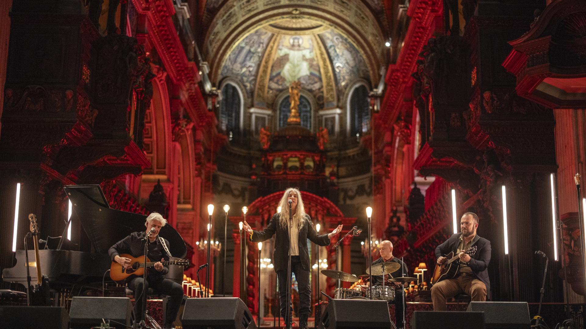 Patti Smith performs a concert under the Dome, surrounded by candles and red lighting.