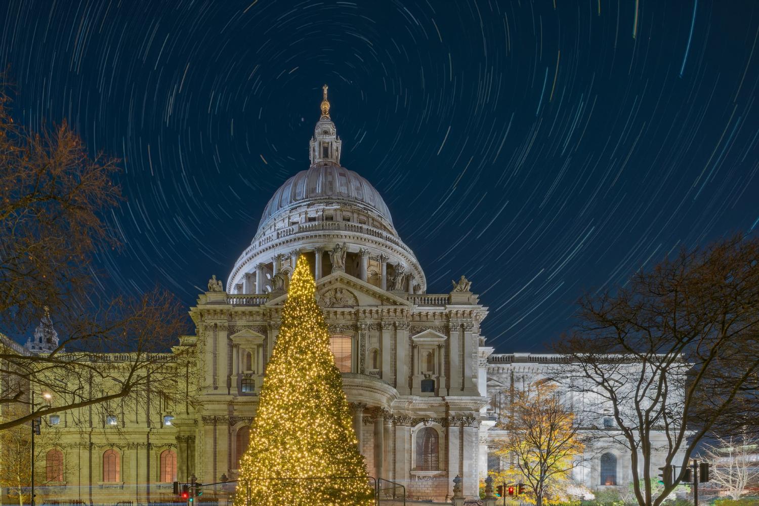 The exterior of St Paul's Cathedral at night with a Christmas tree in the foreground