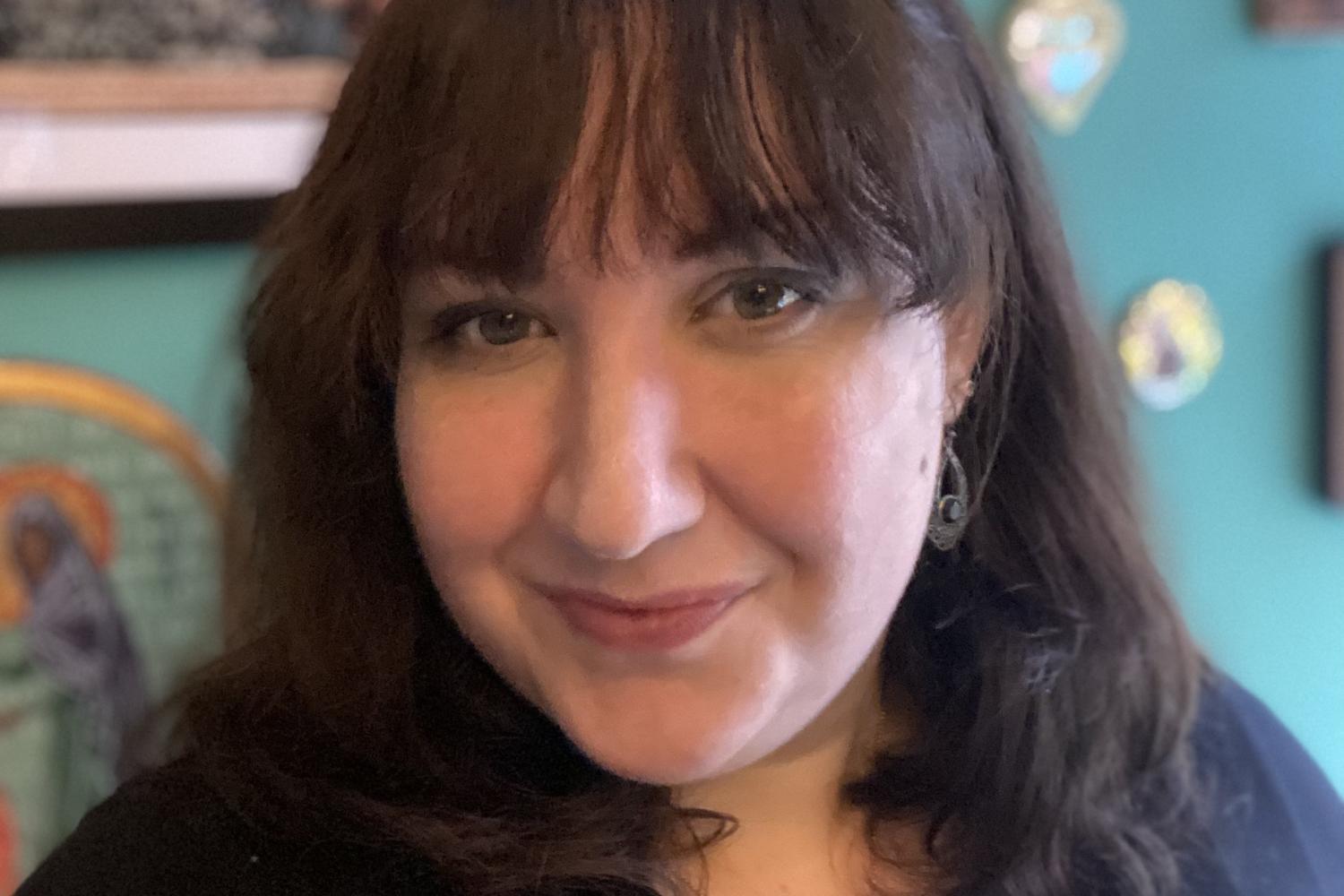 Charlotte Gibson in front of a blue wall covered with artworks