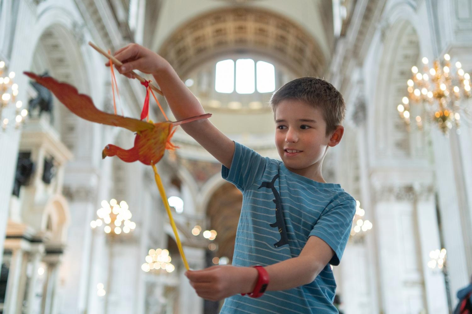 A young boy holds a paper model of a phoenix inside the Cathedral