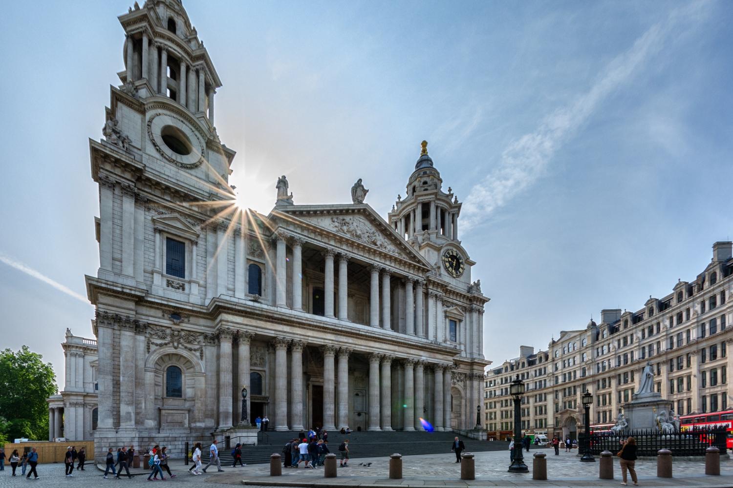 The west front of the cathedral with tourists milling round and sun shining over head