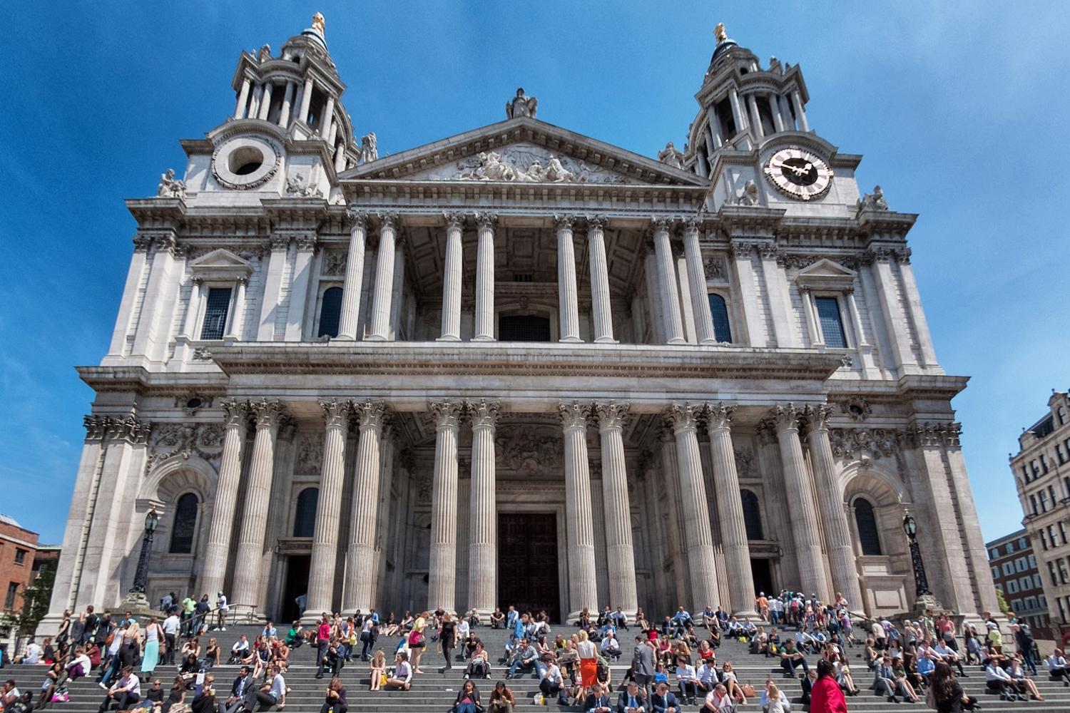 The west front of the cathedral with tourists milling round and sun shining over head