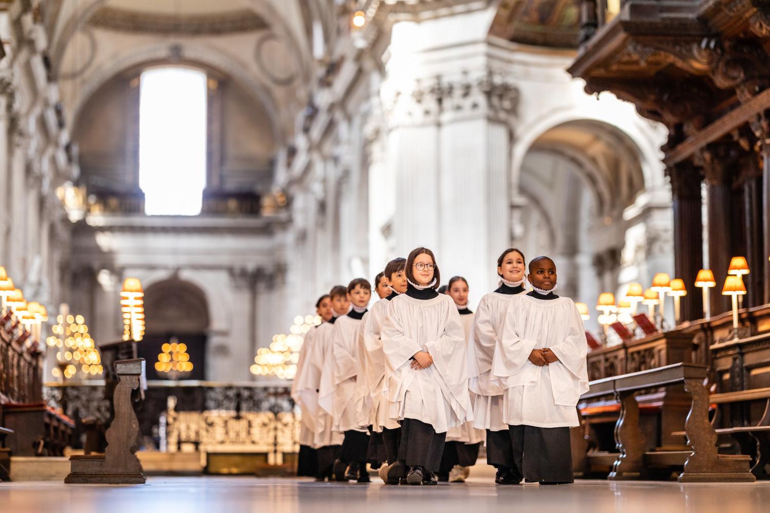 Girl and boy choristers in robes walking in the quire