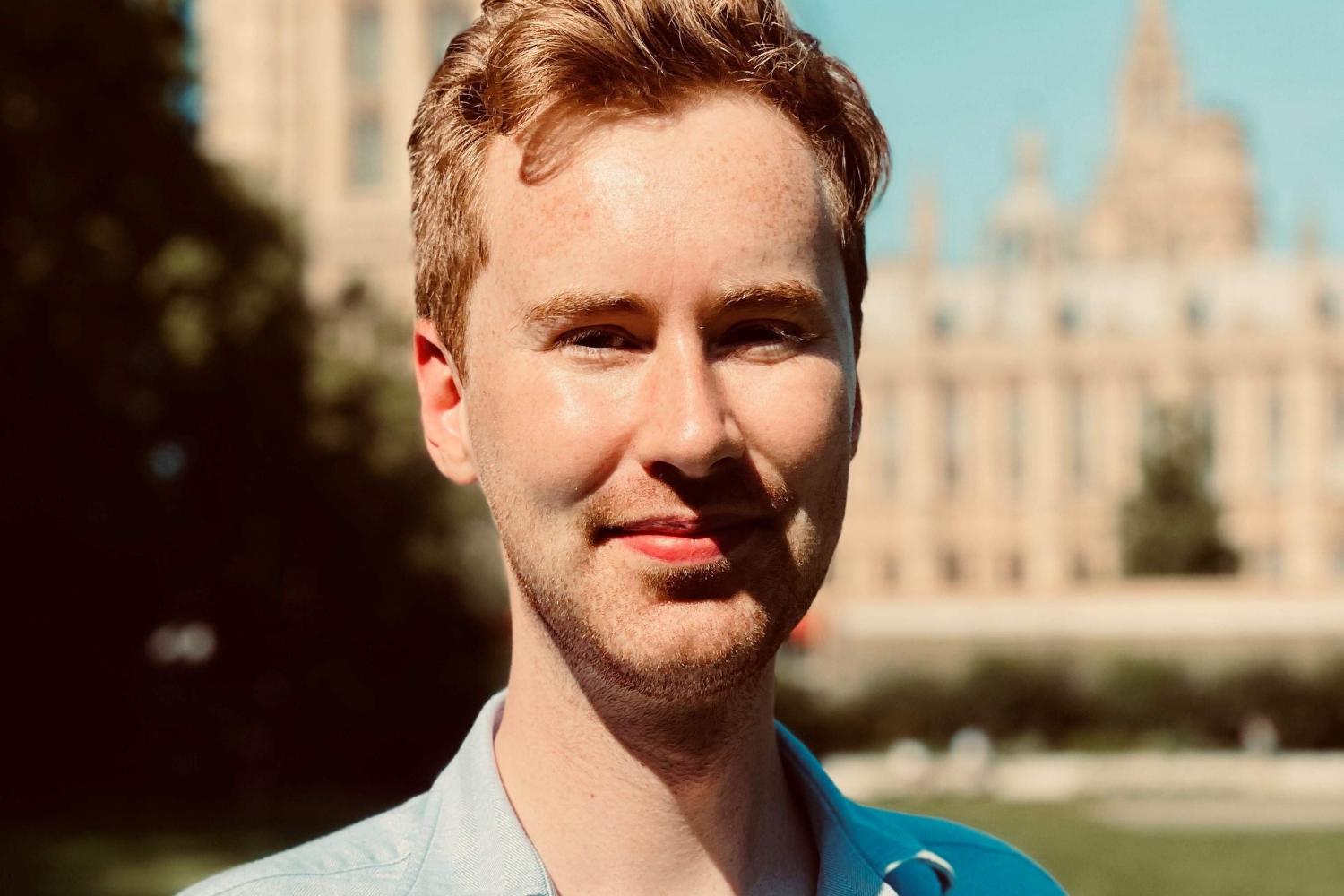 James Roberts, a white male wearing a blue shirt with collar standing in front of a cathedral