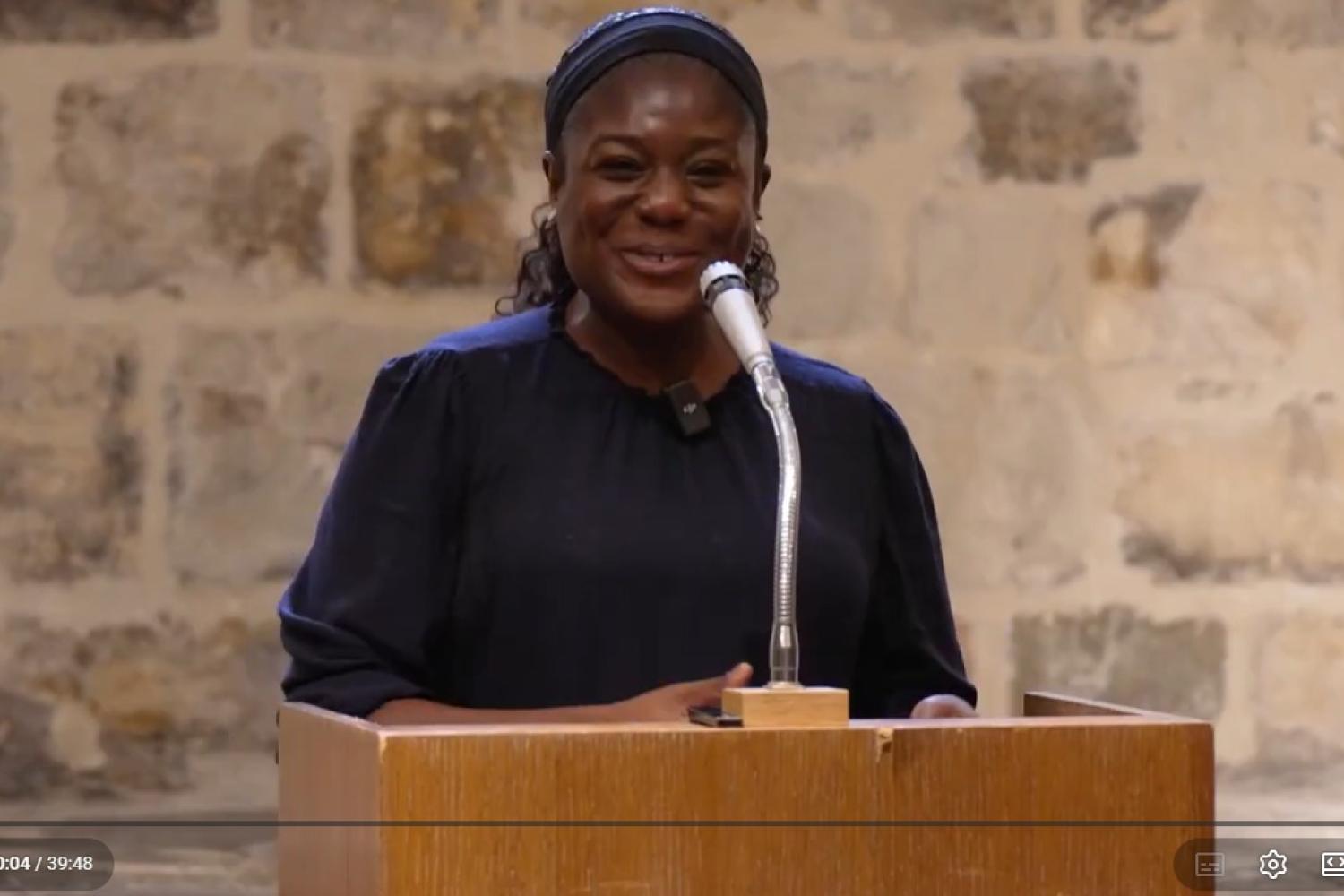 Bisi stands at the microphone and lectern as she delivers a talk in the Wren Suite in St Paul's Cathedral