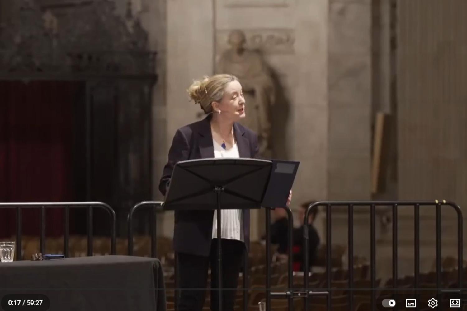 Paula stands at a lectern speaking from a stage in St Paul's Cathedral