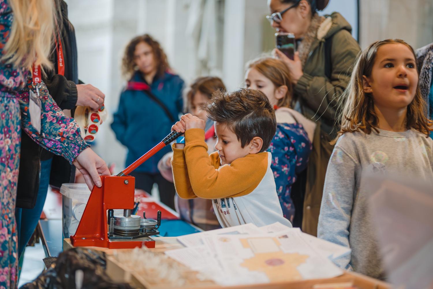 A child pulls down on a large stamp with other children around