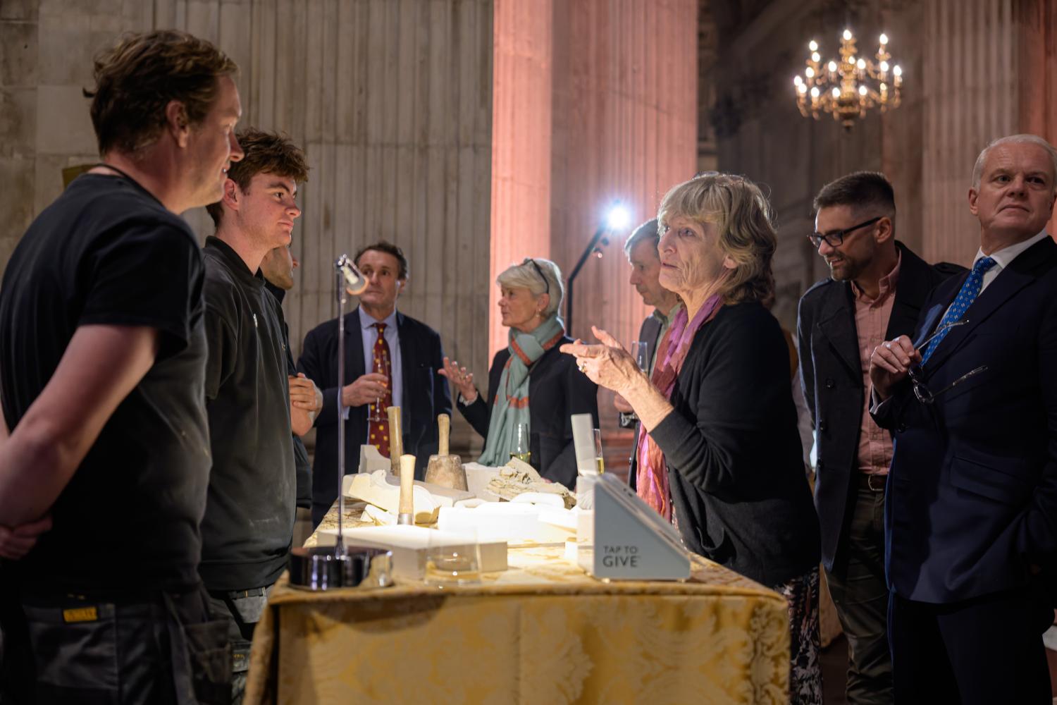 People standing around a table talking with stone carvings in the middle