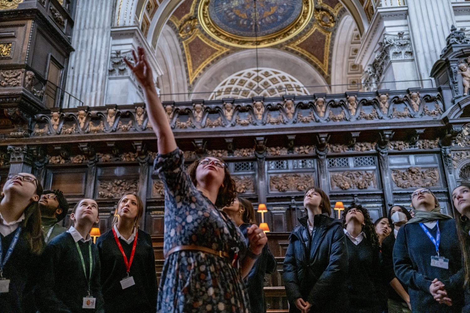 teacher pointing up above heads as children around her look up