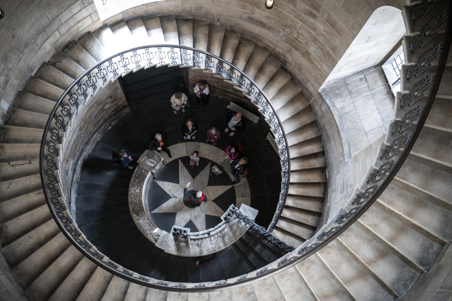 Looking down from the top of the geometric staircase, with visitors at the bottom.