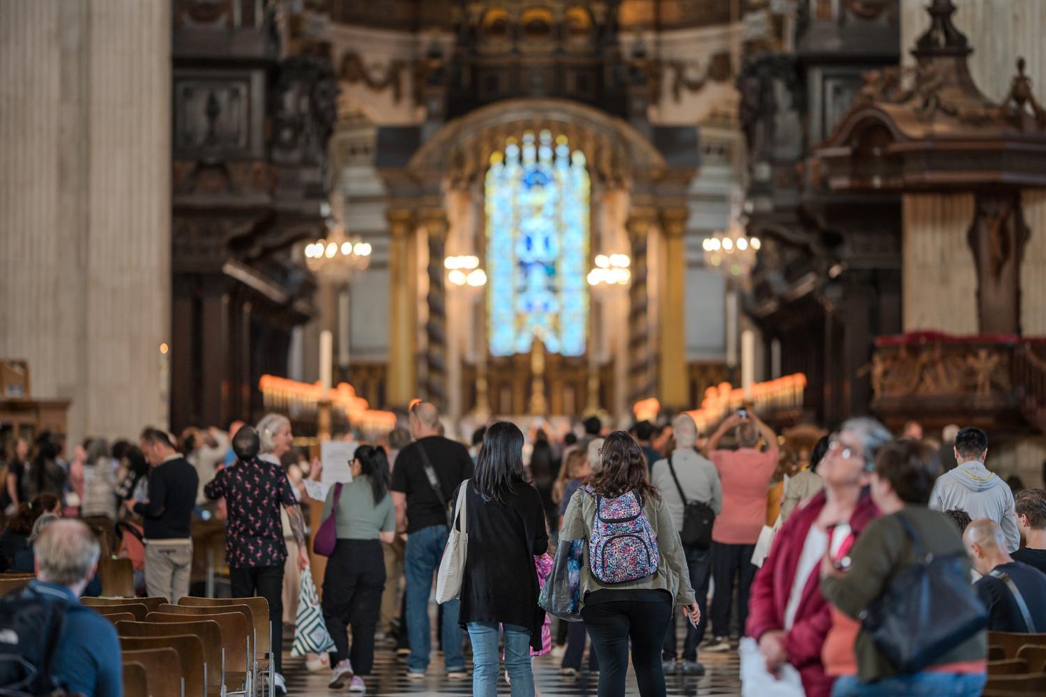 A large number of people wander around the nave of the cathedral, looking around them as they walk